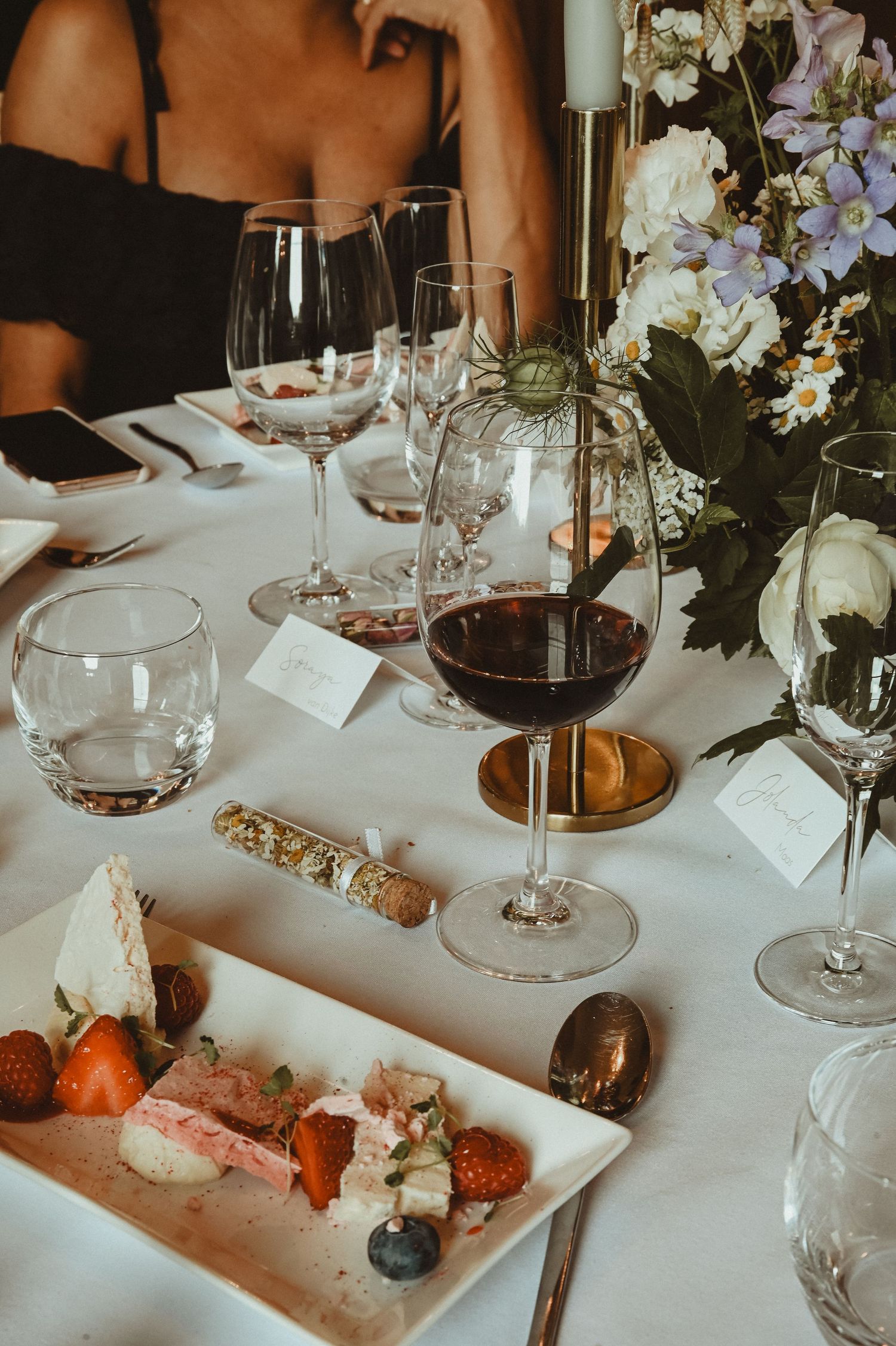 Fine dining table setting with wine glasses, floral arrangements and gourmet appetizers.