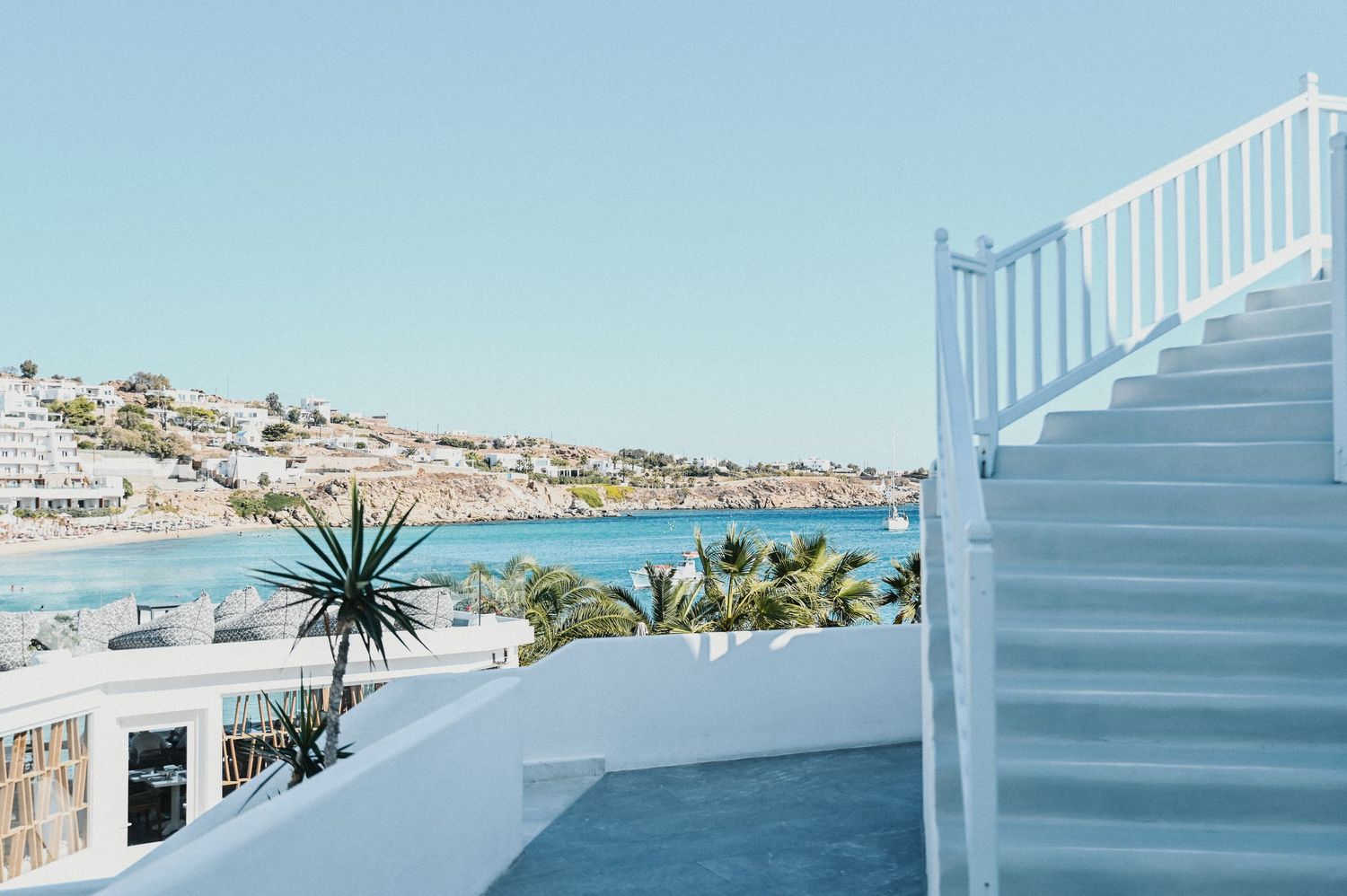 White Mediterranean architecture with stairs overlooking coastal town and sea view.