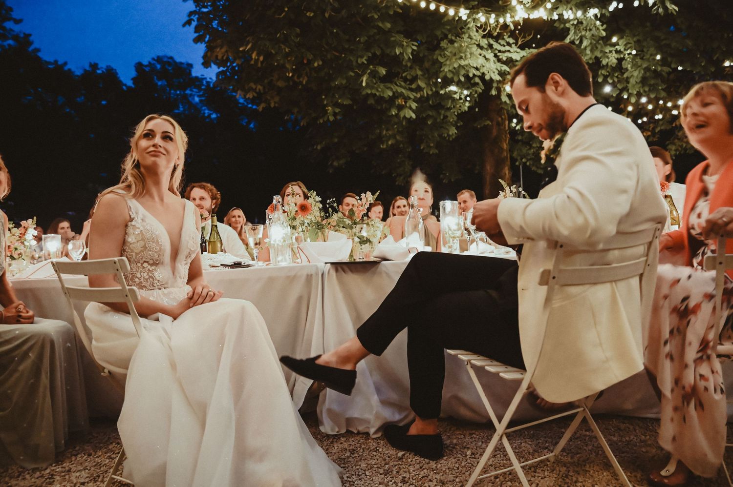 Evening wedding reception under string lights with elegant table settings and romantic atmosphere.