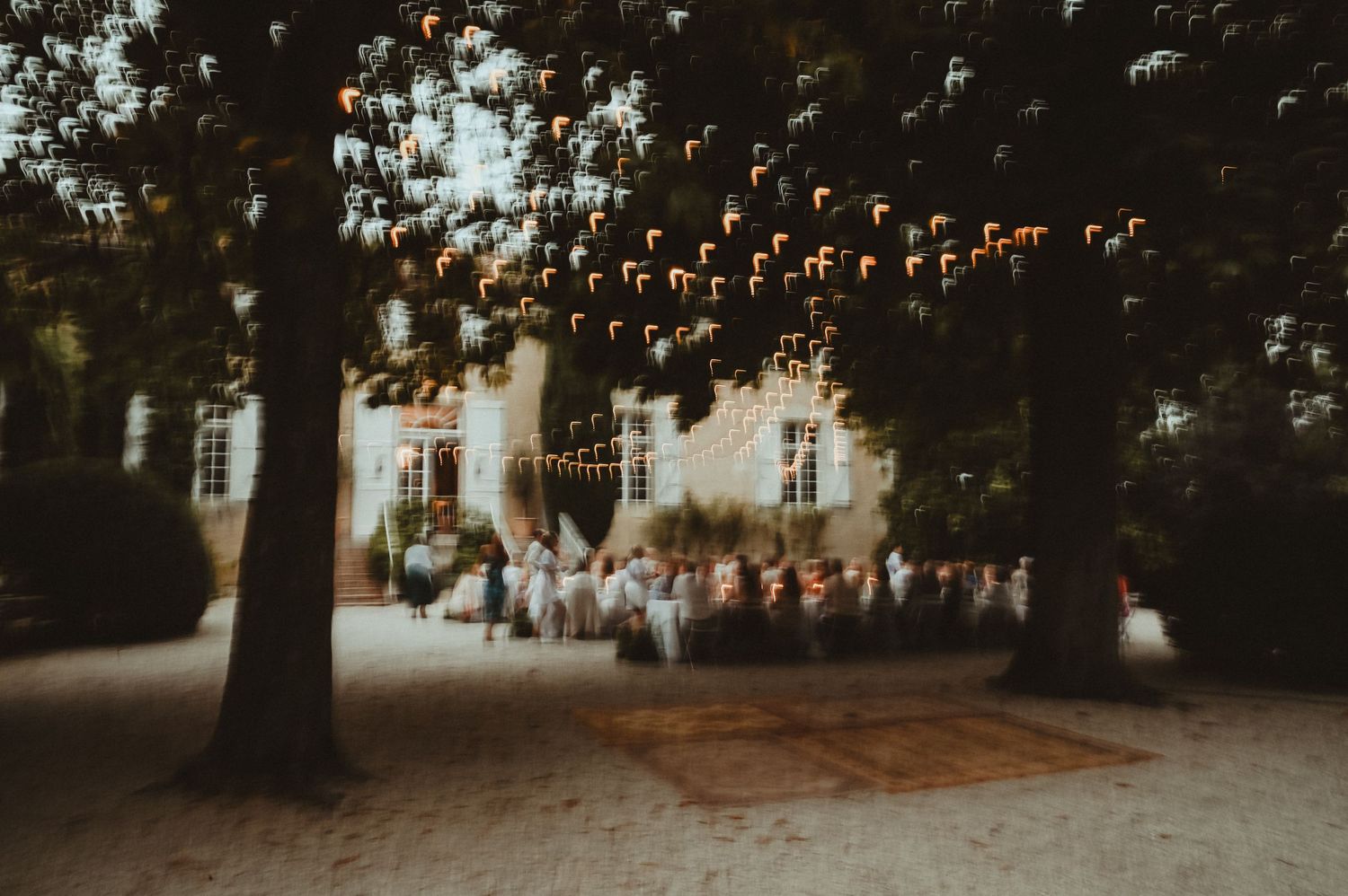 String lights create a magical ambiance over an outdoor evening gathering in a garden setting.