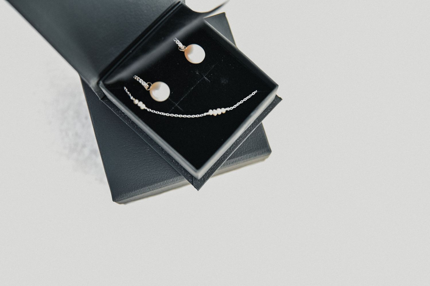 Pearl and silver jewelry set displayed elegantly in a black box.