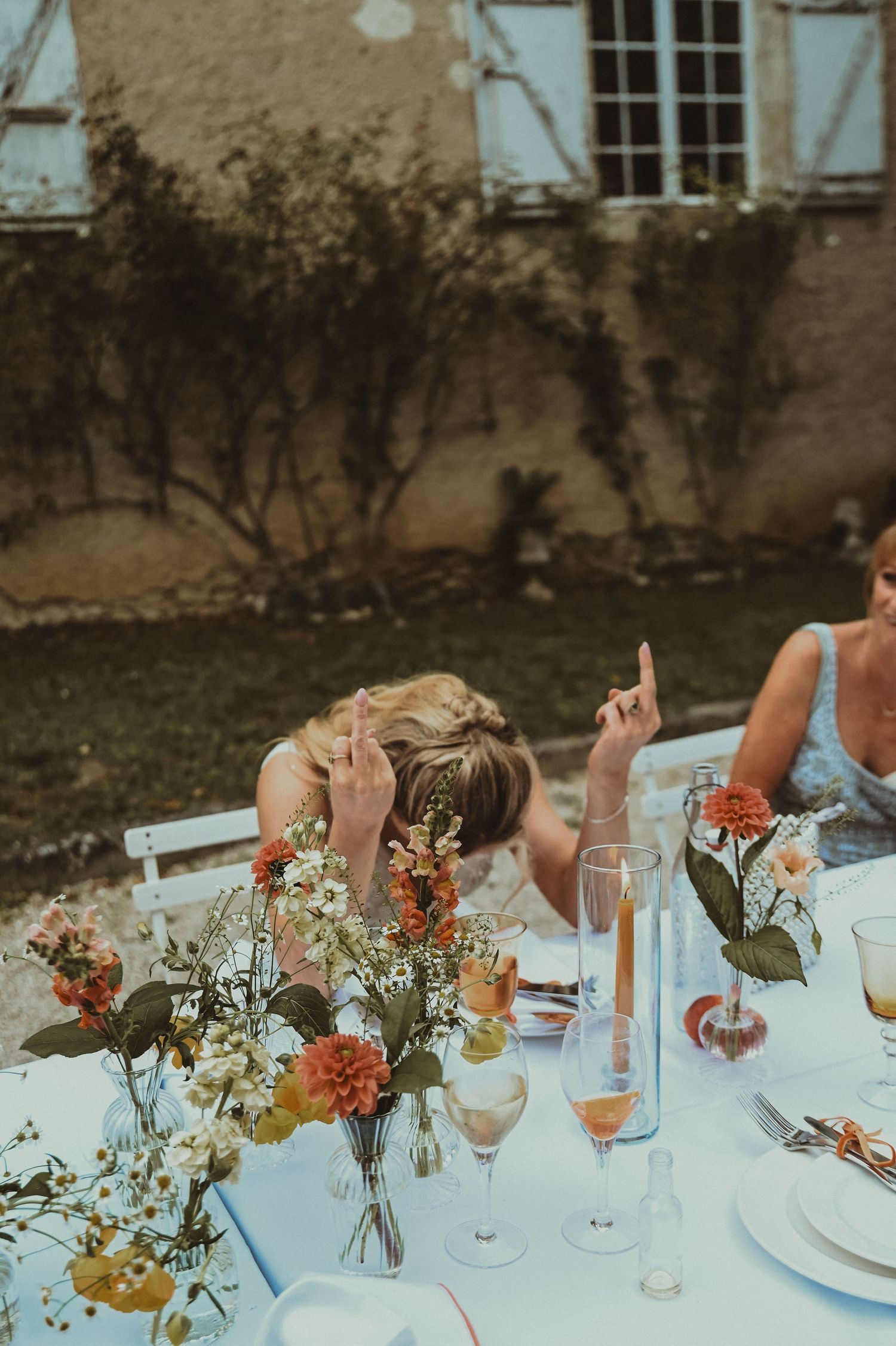 Floral table settings with orange and white flowers at outdoor wedding reception.