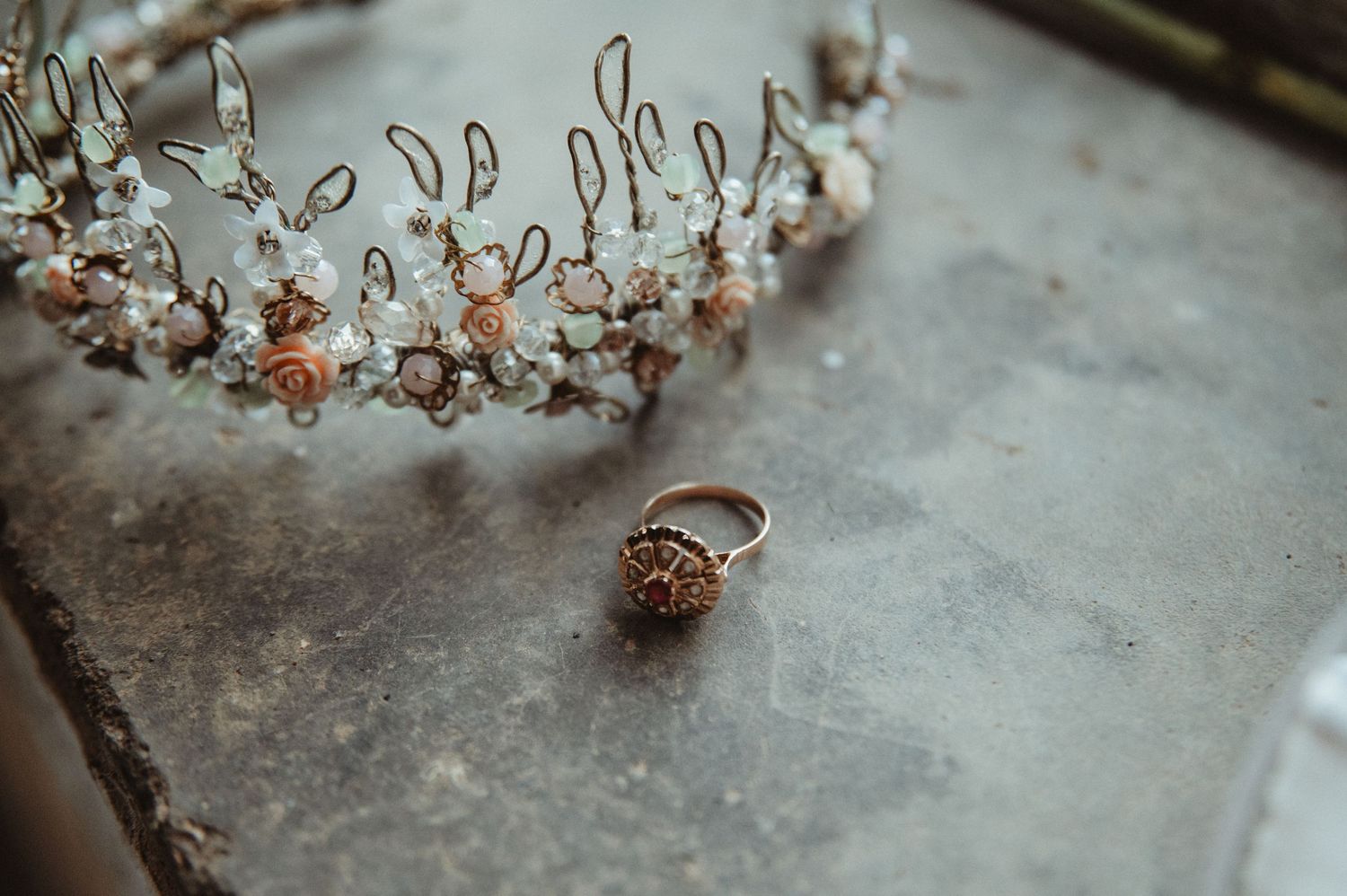 Delicate wire crown and vintage ring photographed on weathered surface.