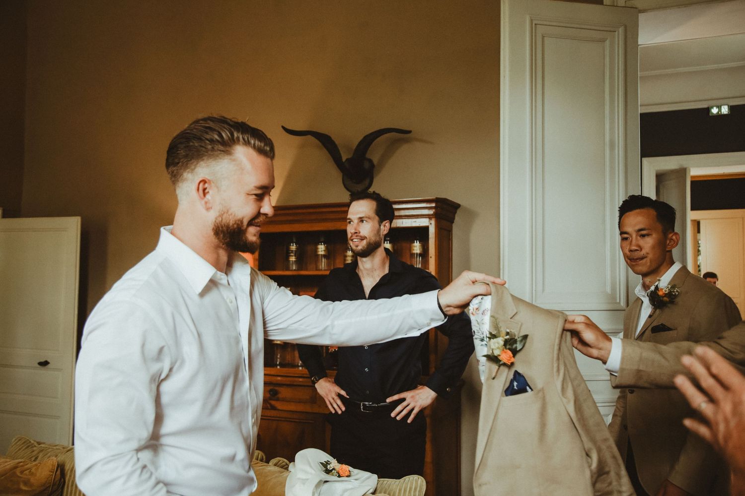 Groomsmen sharing a celebratory moment during wedding preparations.