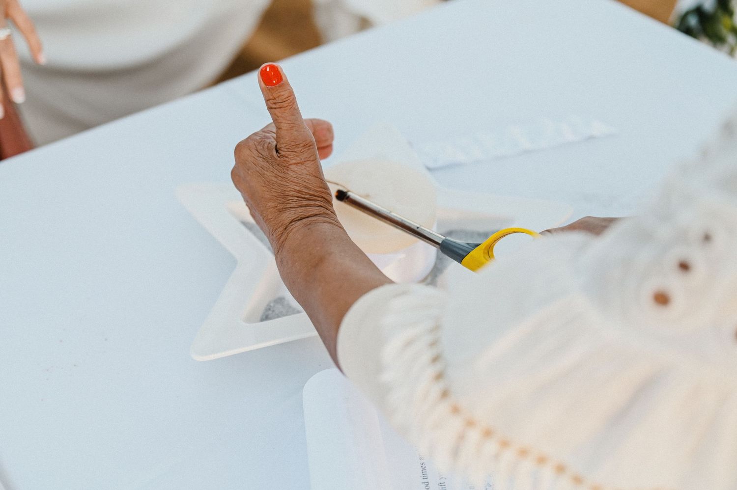 Close-up of hand writing on white paper during wedding celebration.