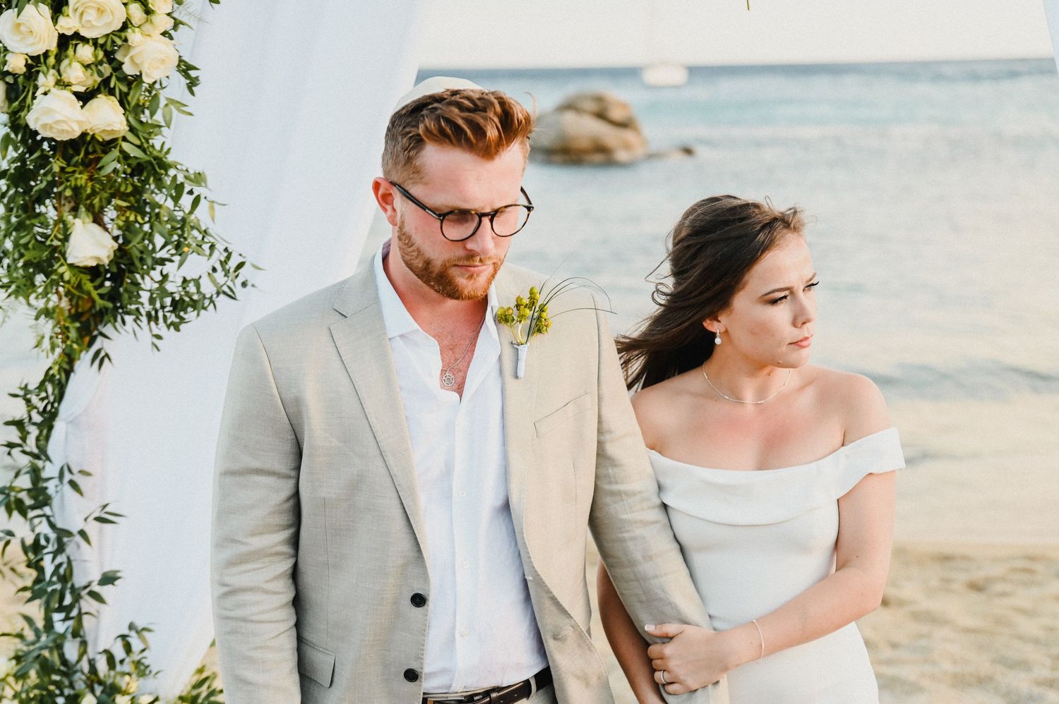 Elegant beach wedding ceremony setup with floral arch and ocean backdrop.