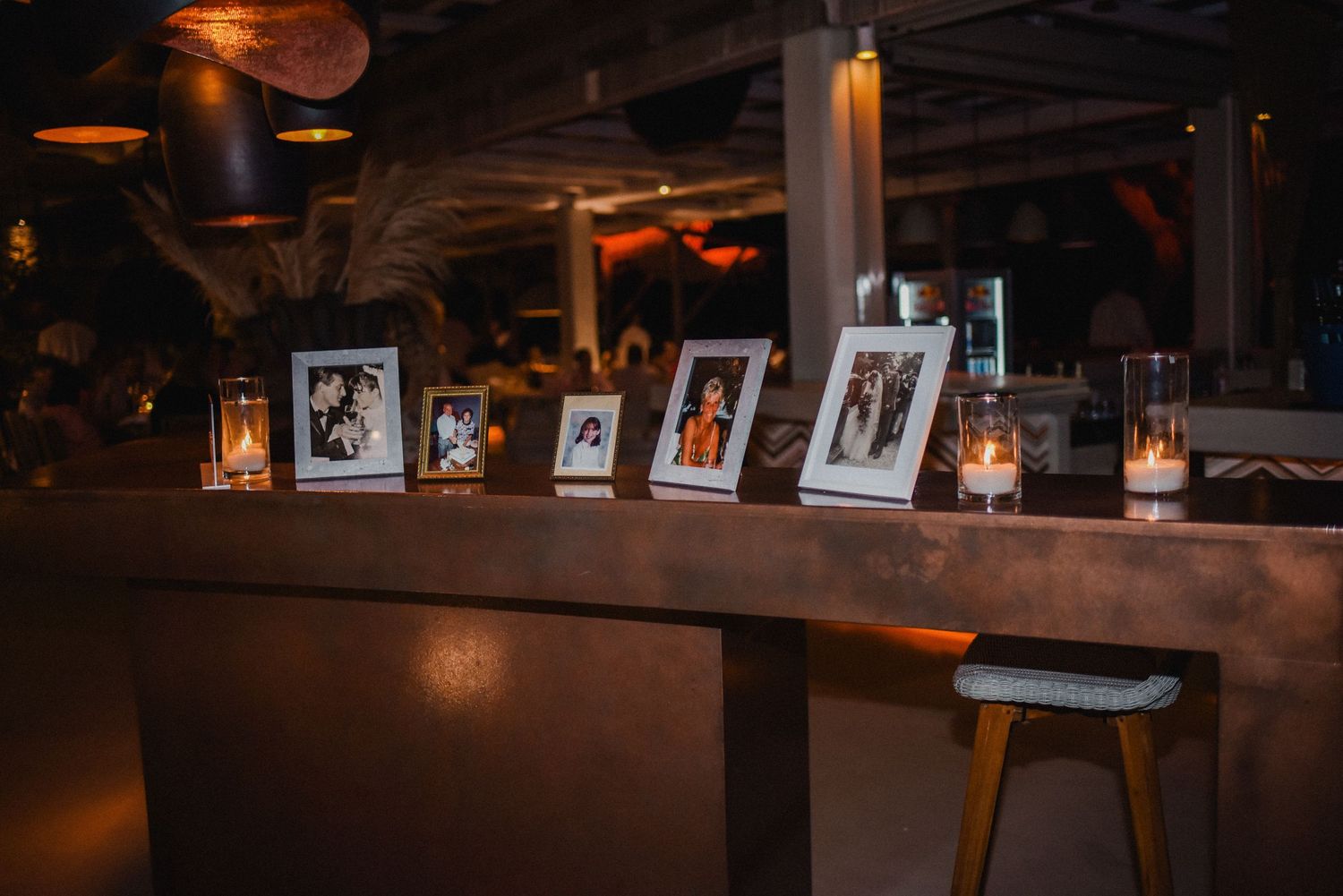 Framed photographs displayed on a wooden shelf with candlelight creating romantic ambiance.