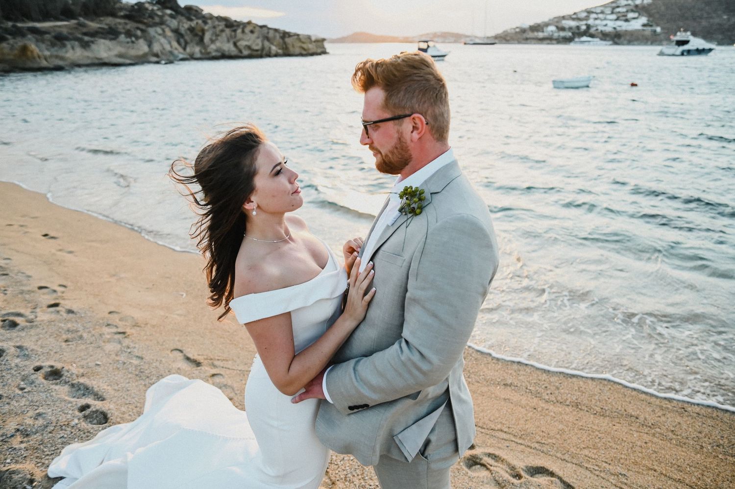 A couple shares an intimate moment on a windy beach during their wedding photography session.