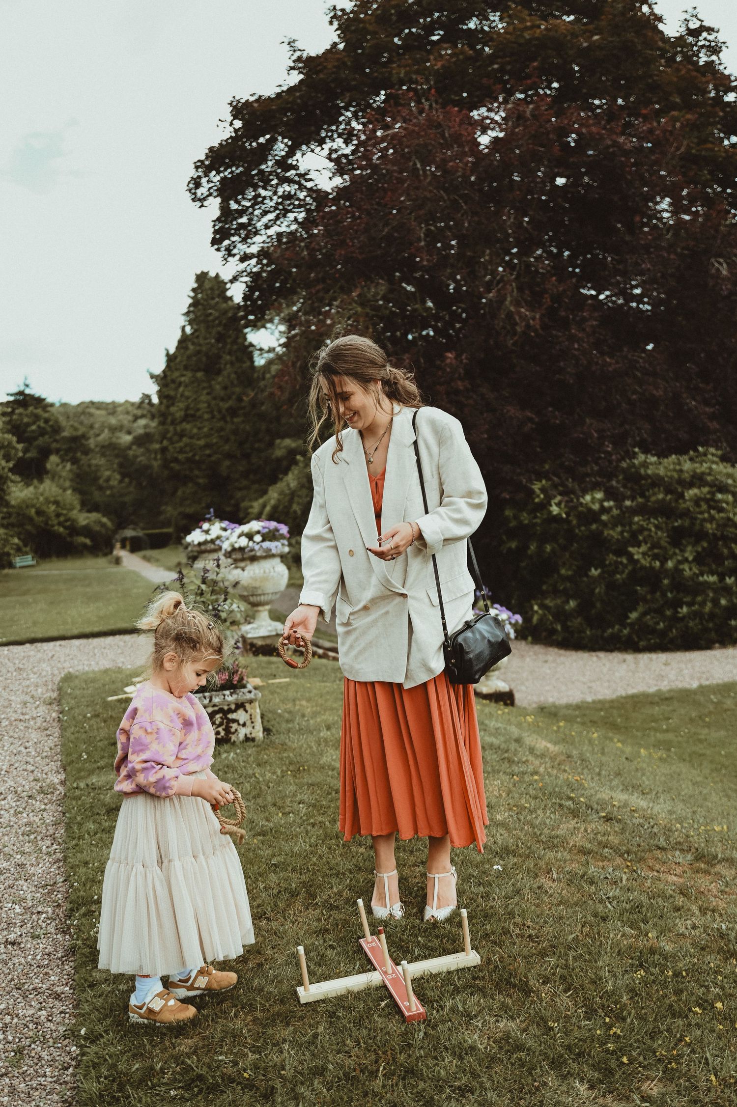 Two people playing garden games on a path surrounded by lush greenery.