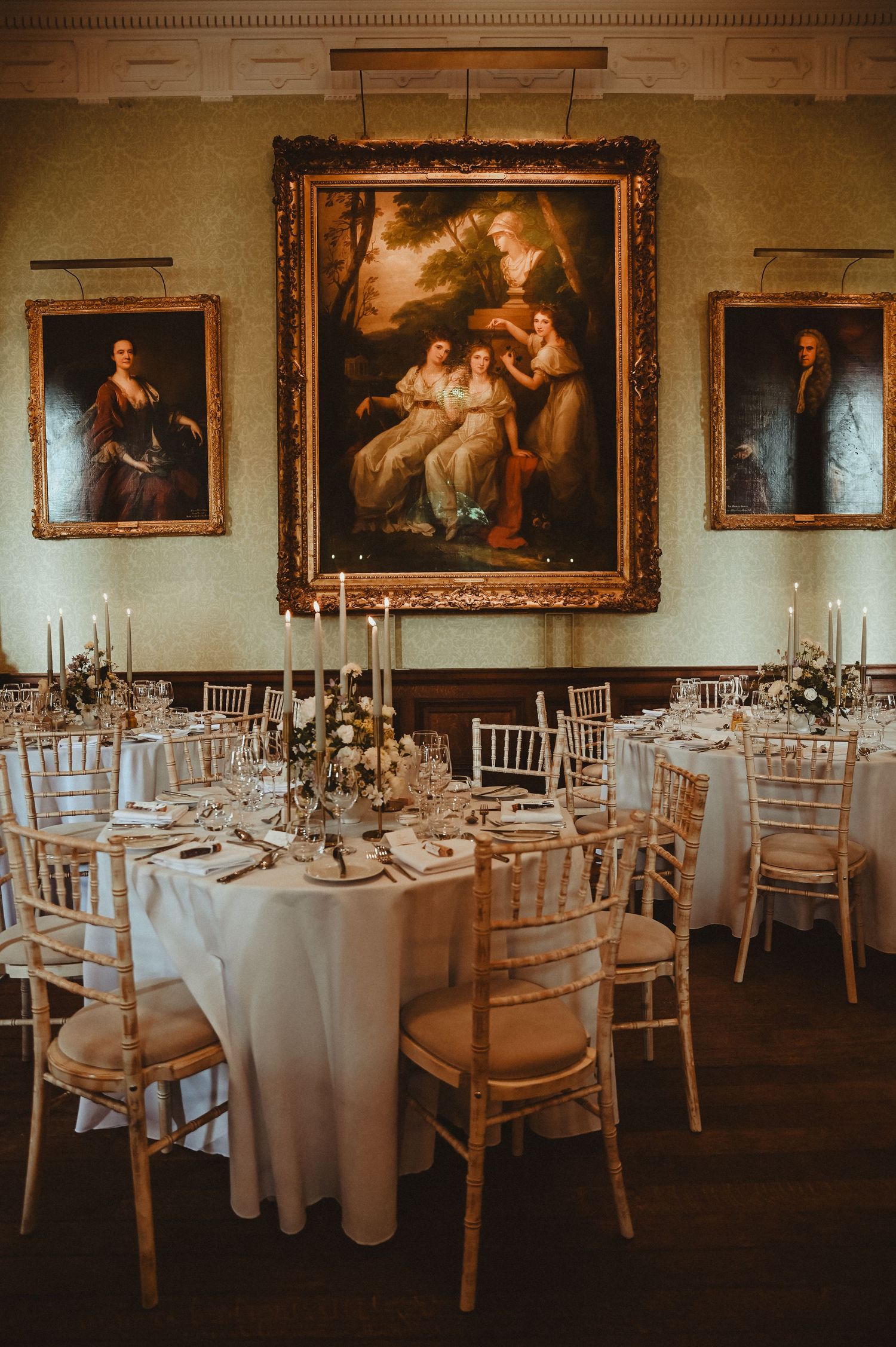 Elegant wedding reception dining room with classical paintings and formal table settings.