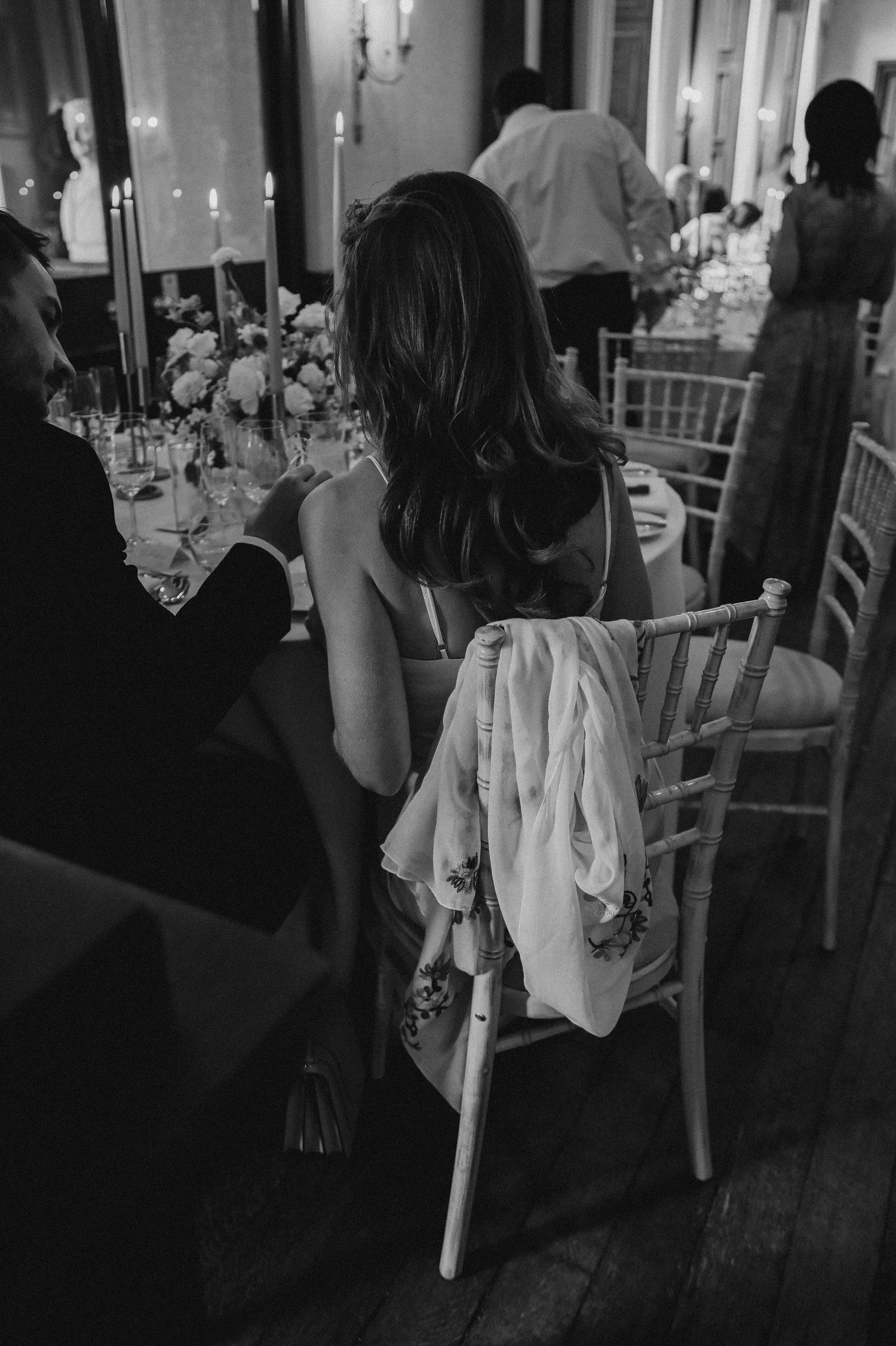 Black and white photo of wedding reception dinner table with candlelight and elegant place settings.
