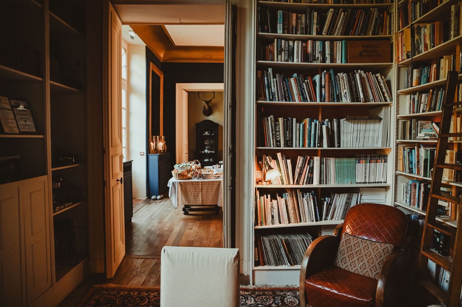 Cozy library room with floor-to-ceiling bookshelves and comfortable reading chair.