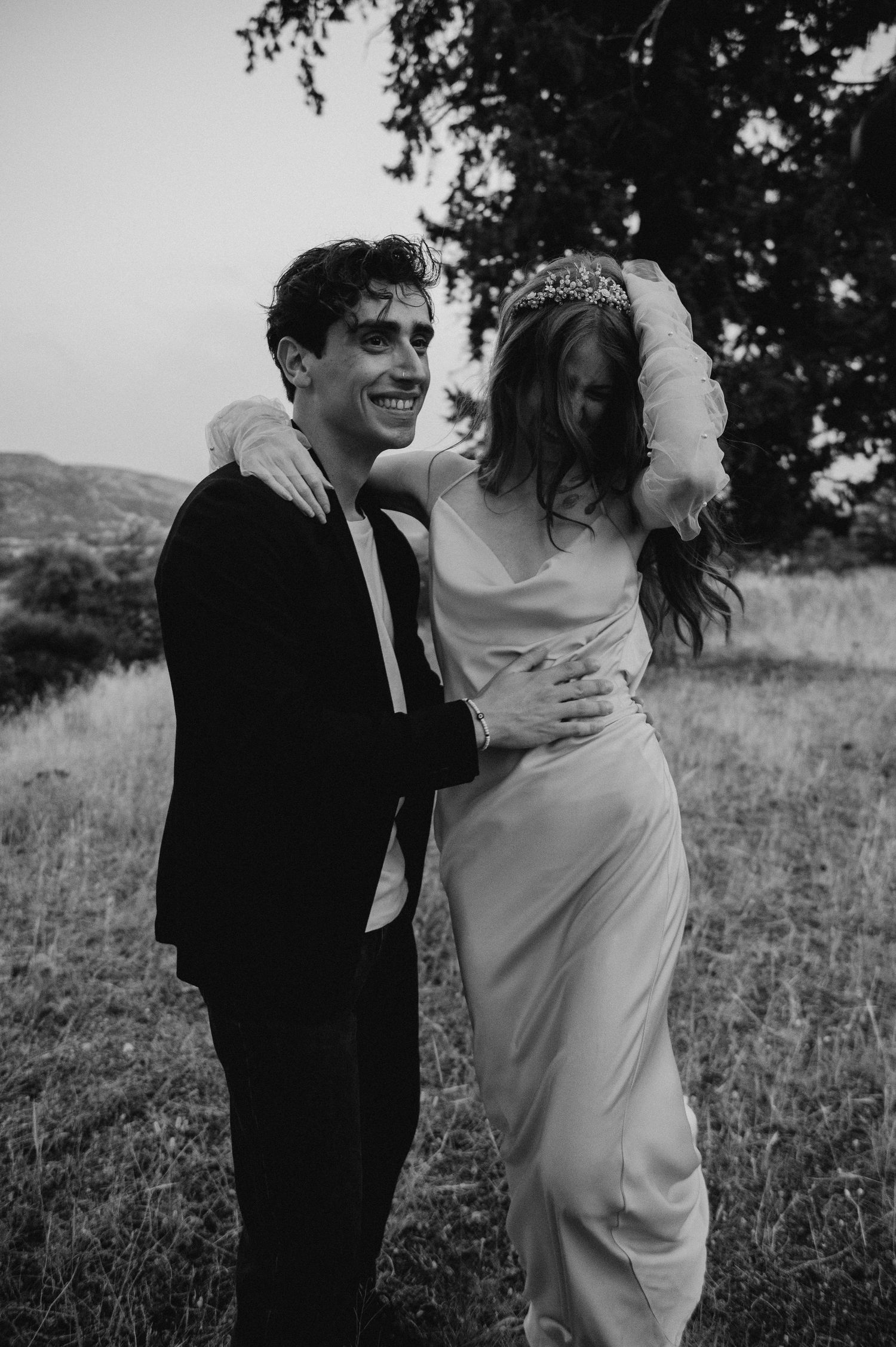 A joyful candid moment between a couple in formal attire outdoors.