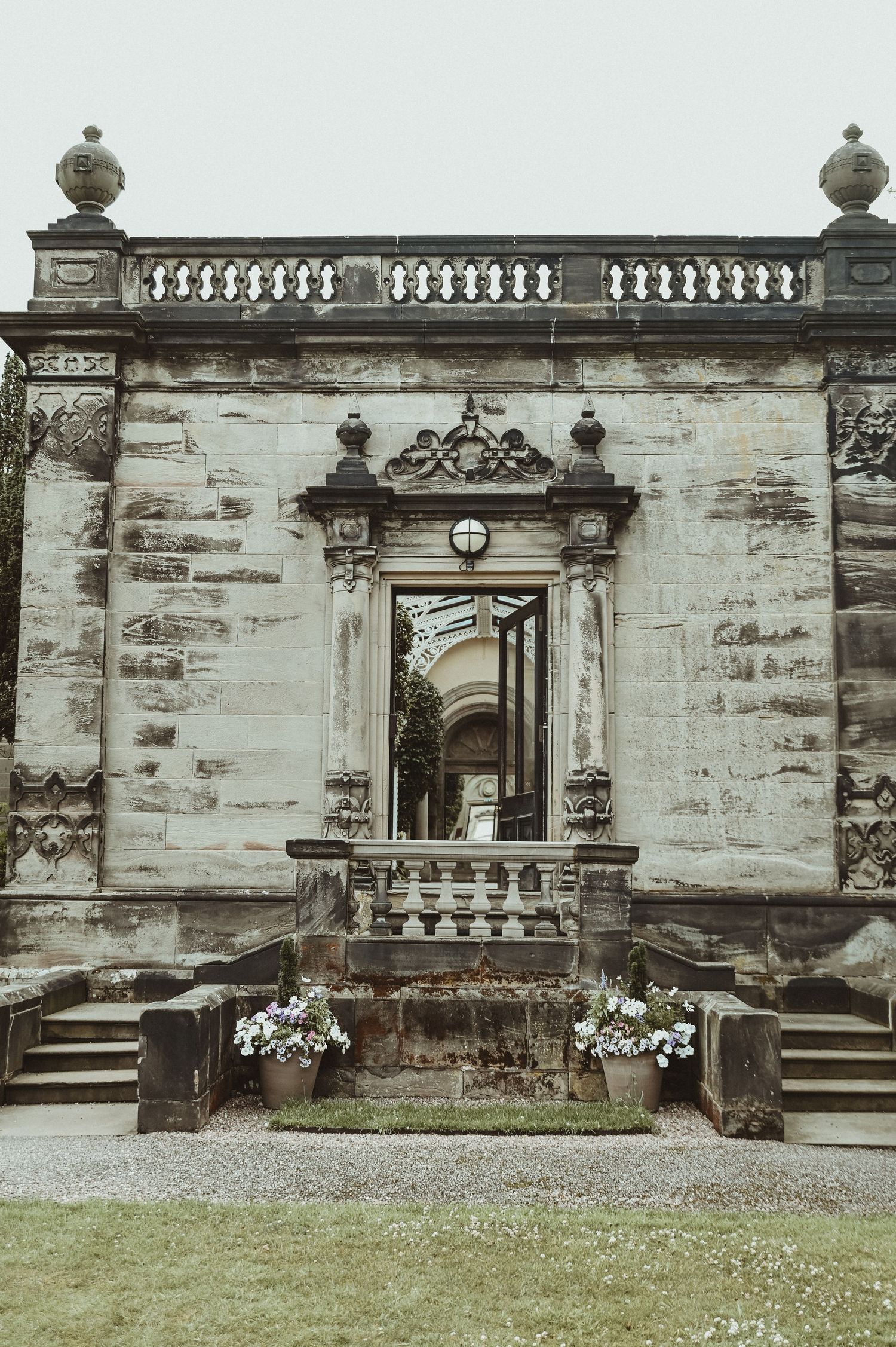 Ornate stone entrance with decorative balustrade and classical architectural details at a grand estate.