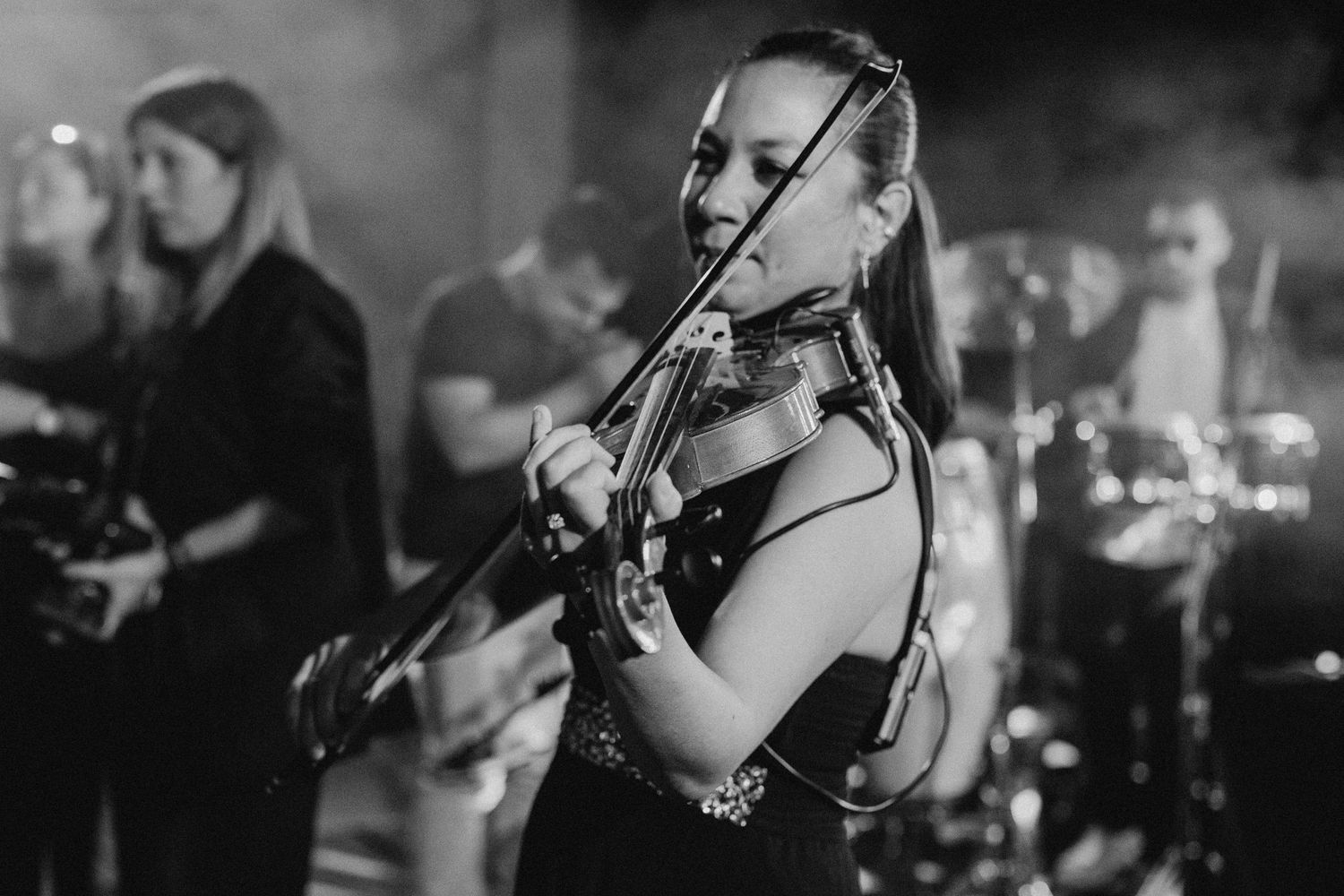 Female violinist performs with band during wedding reception.