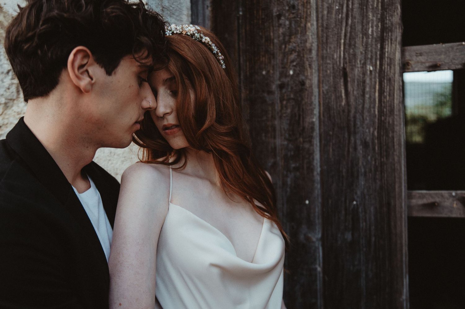 A tender moment captured against weathered wood in natural light.