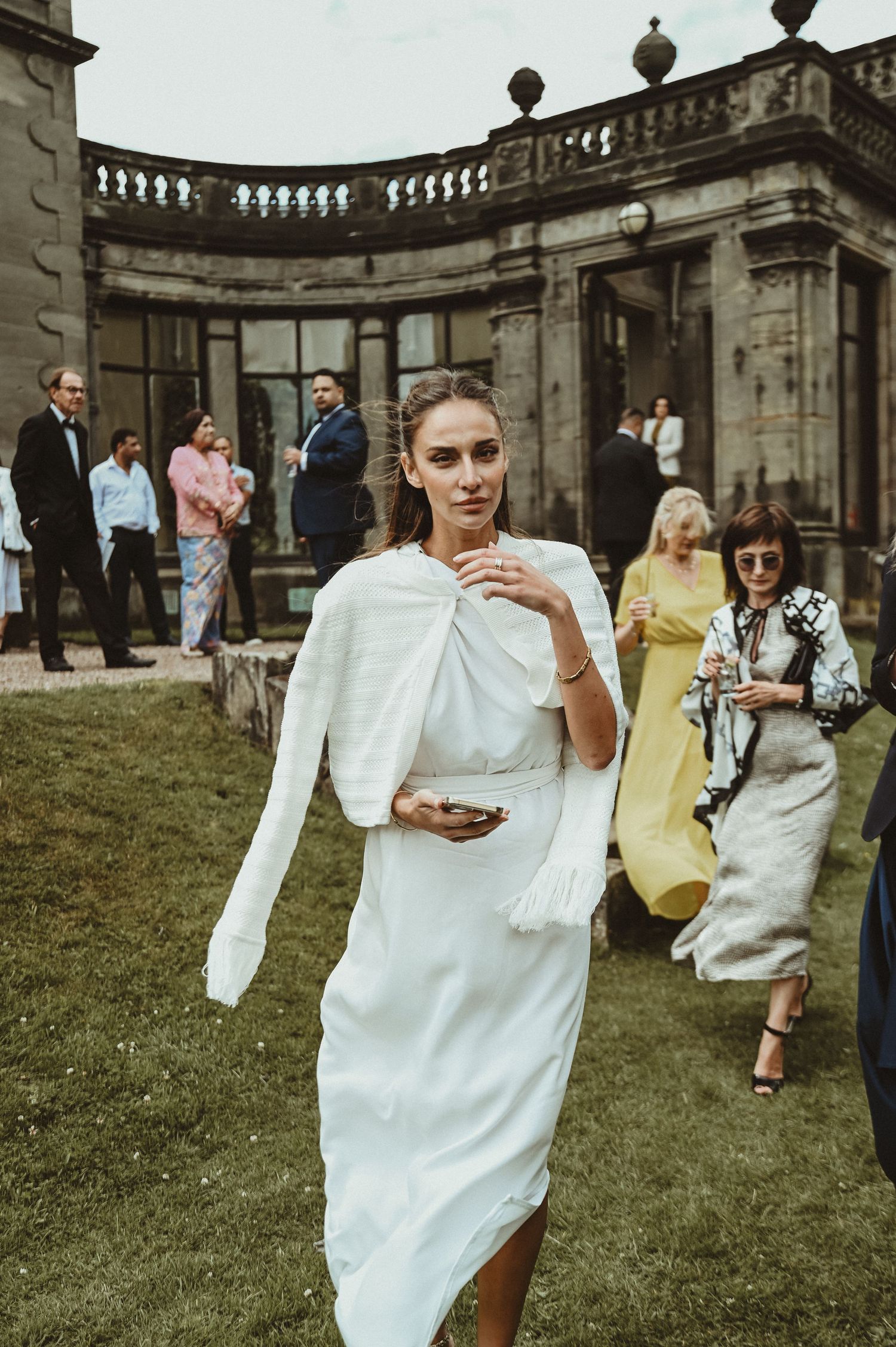 An elegant wedding celebration at a historic venue with guests in formal attire on the lawn.