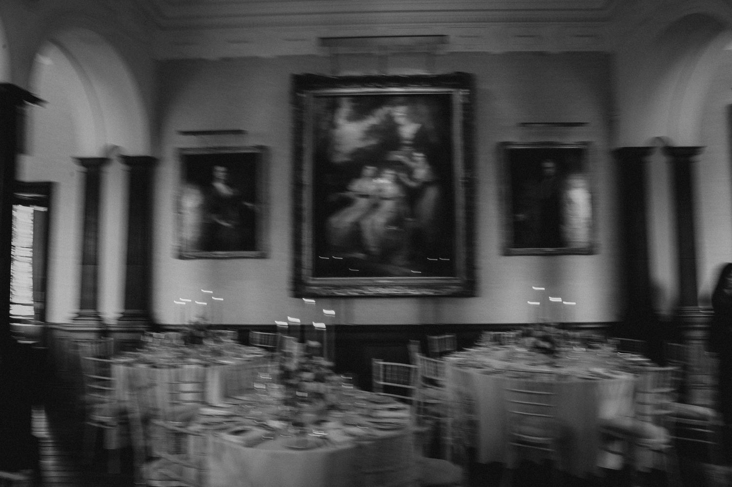 Elegant dining room with classical artwork and formal table settings in black and white.