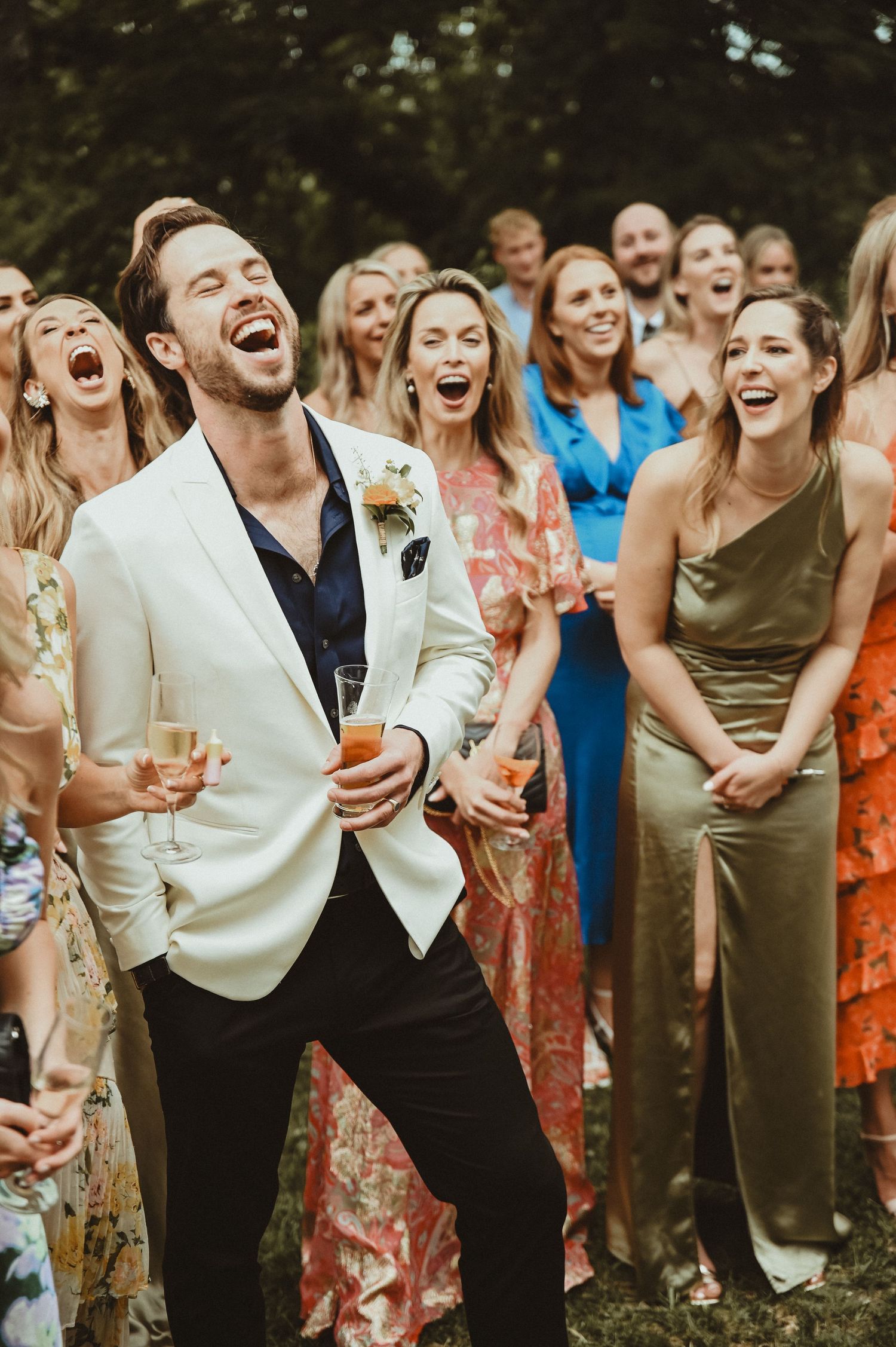 Festive celebration at outdoor wedding with guests laughing and enjoying champagne.