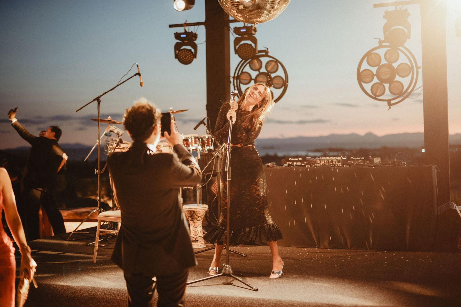 Band performs on outdoor stage at sunset with decorative lighting elements.