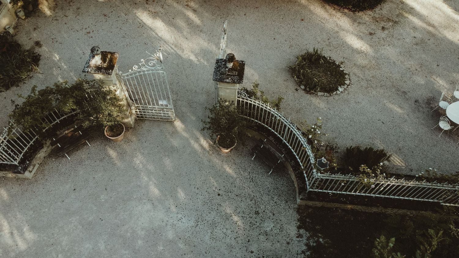 Aerial shot of ornate white entrance gates with curved design viewed from above.