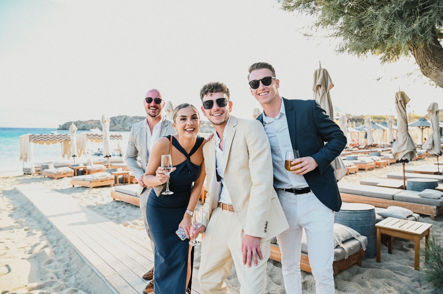 Wedding guests enjoying cocktail hour at beachside venue with lounge furniture.