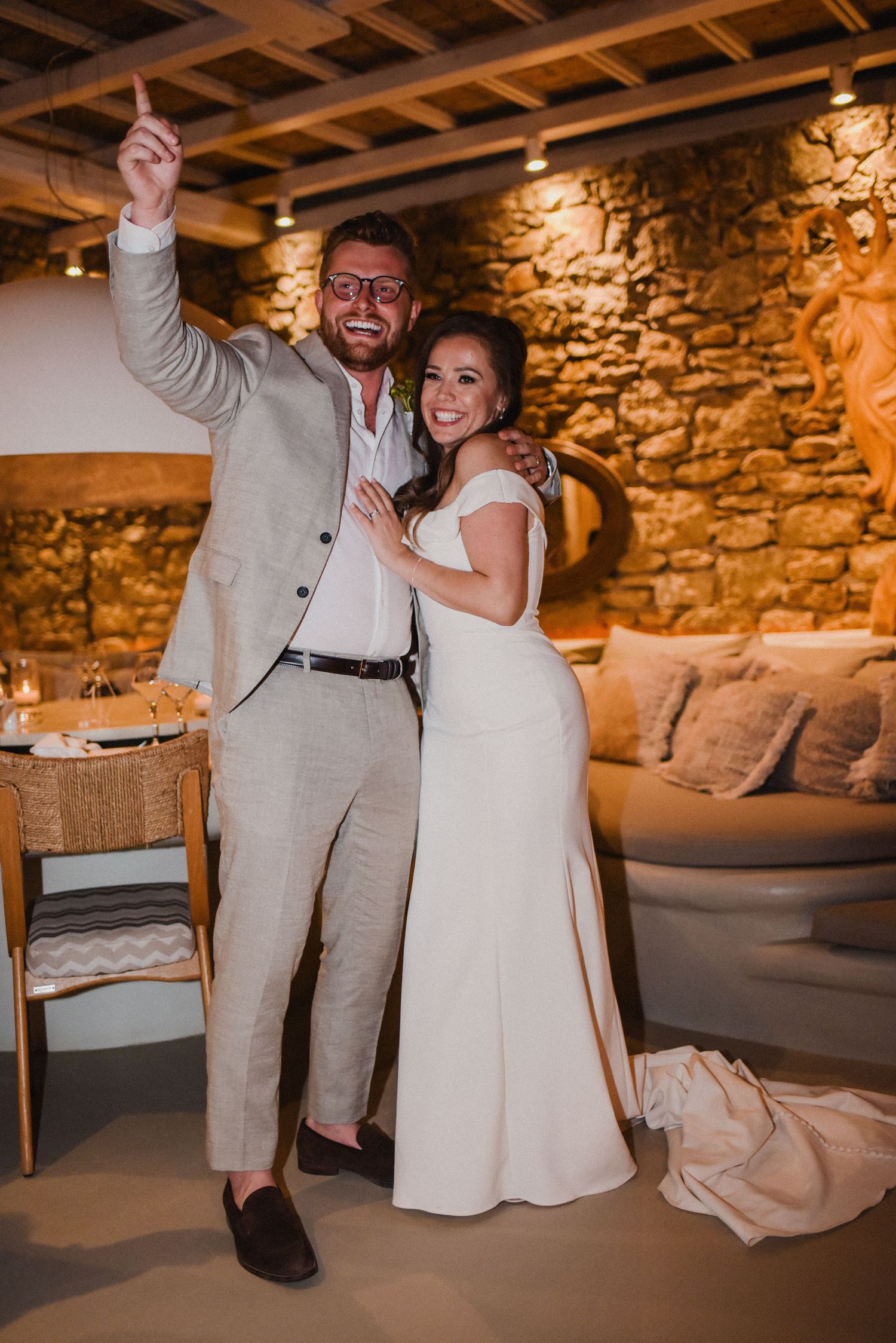 A couple dancing and celebrating at their wedding reception in an intimate stone-walled venue.