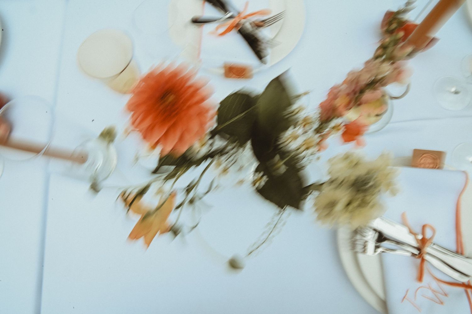 Abstract blurred image of orange and pink floral arrangements on a white surface.
