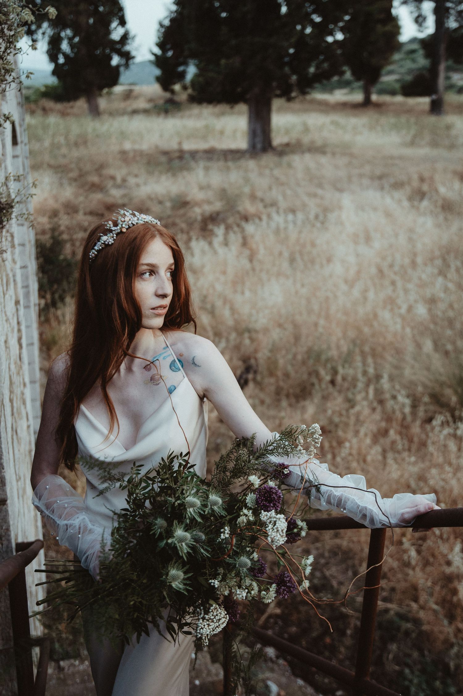 Ethereal bridal portrait in a meadow with wild bouquet and flowing dress.