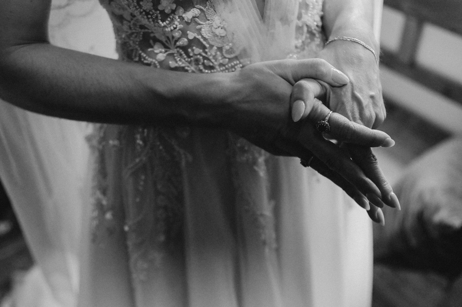 Black and white close-up of hands against a flowing white dress fabric.