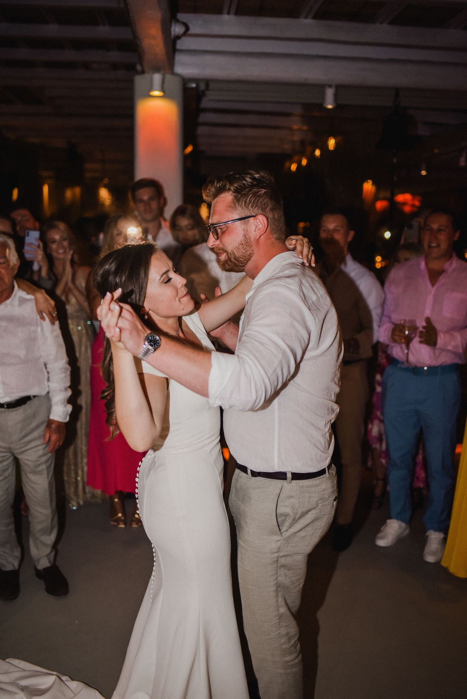 Dancing couple shares a romantic moment on the reception dance floor surrounded by wedding guests.