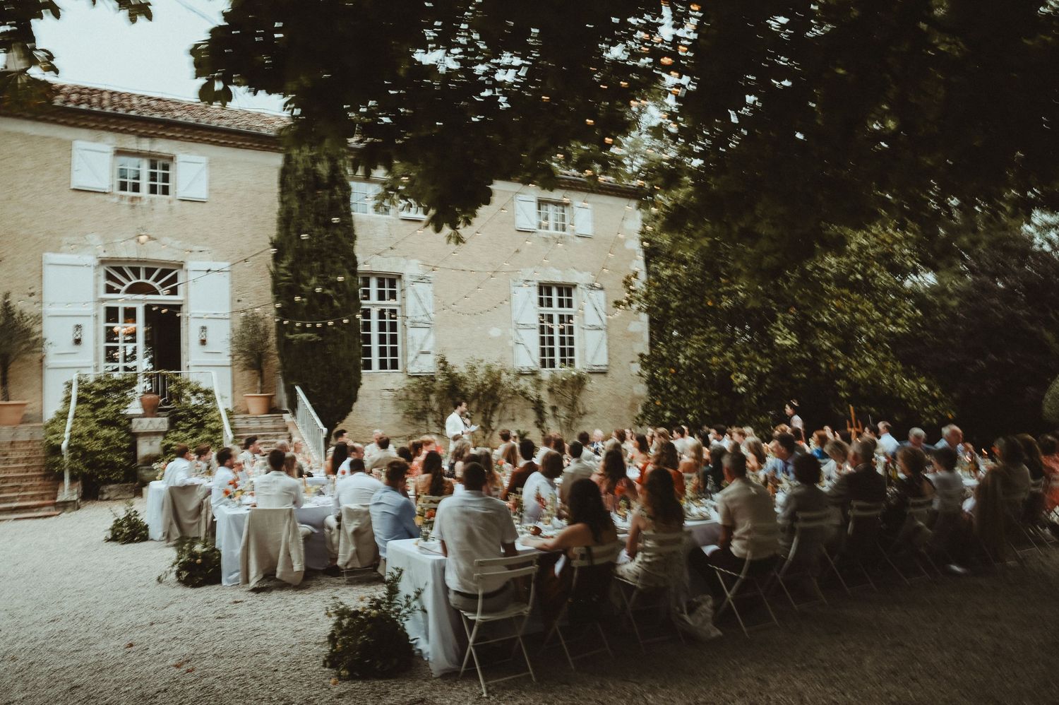 Aerial view of outdoor wedding reception at French countryside villa with white table settings.