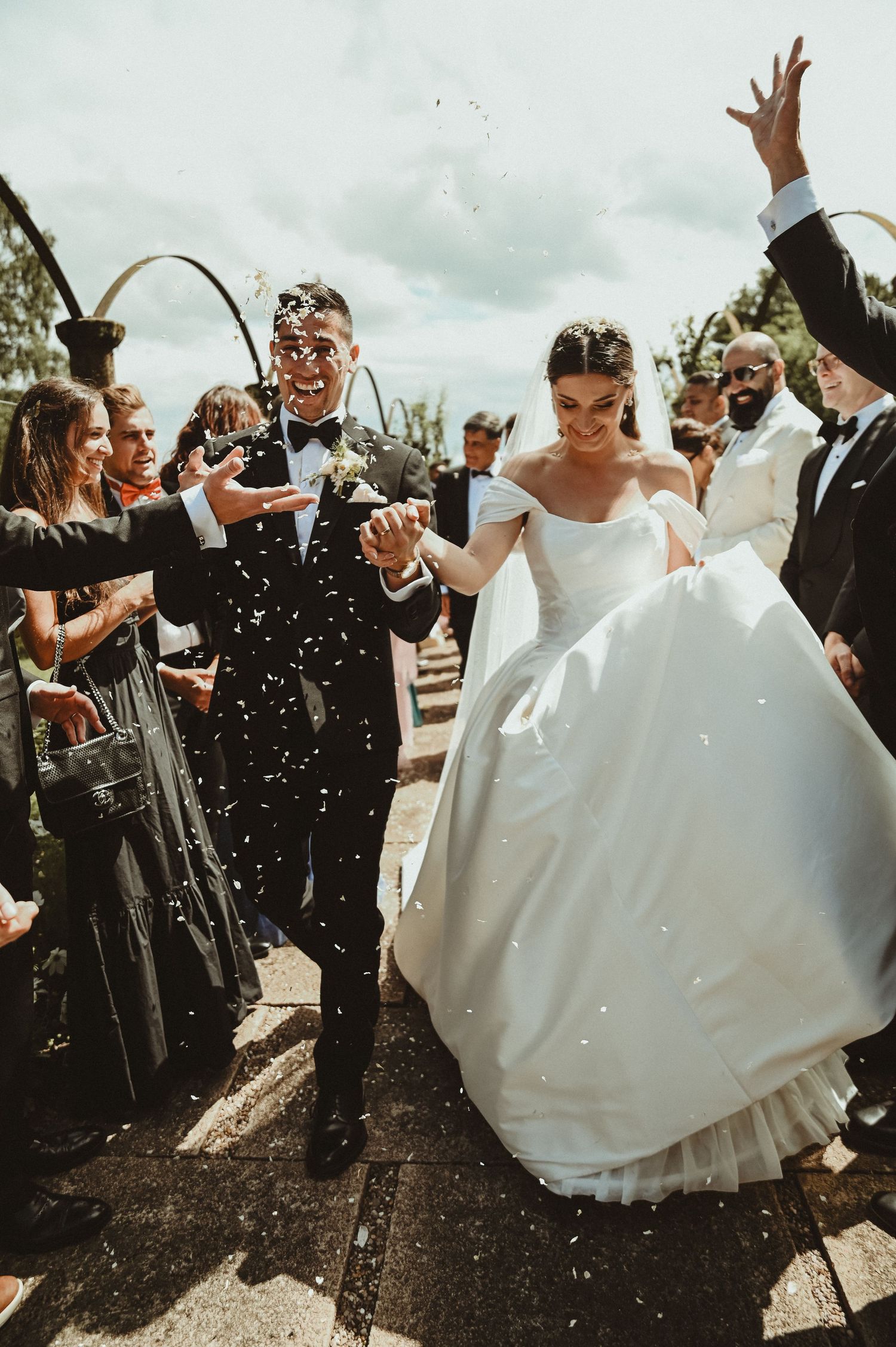 Newlyweds celebrate with guests as confetti falls during their wedding ceremony exit.