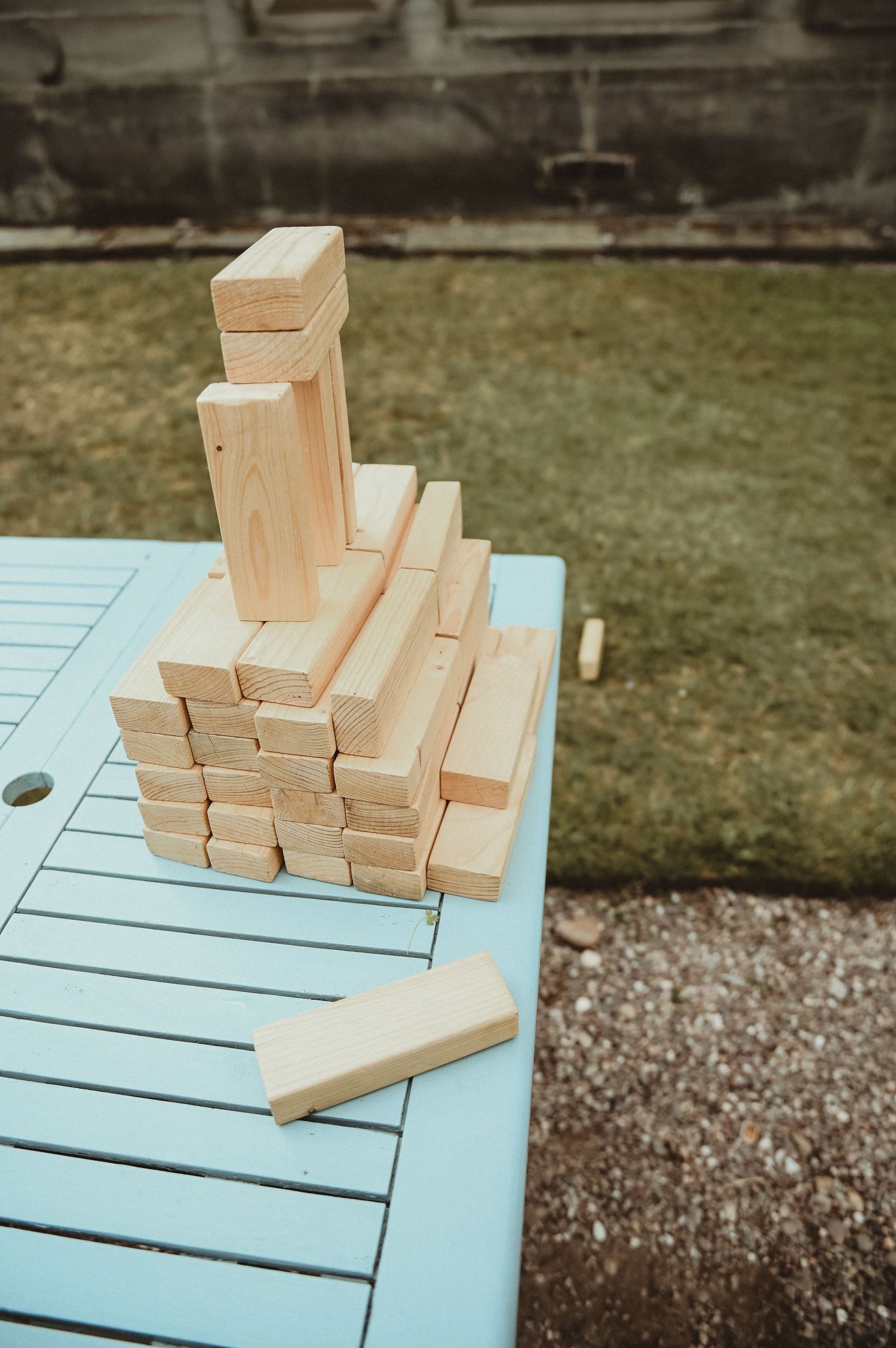 Wooden Jenga blocks stacked on a blue table during outdoor wedding reception games.