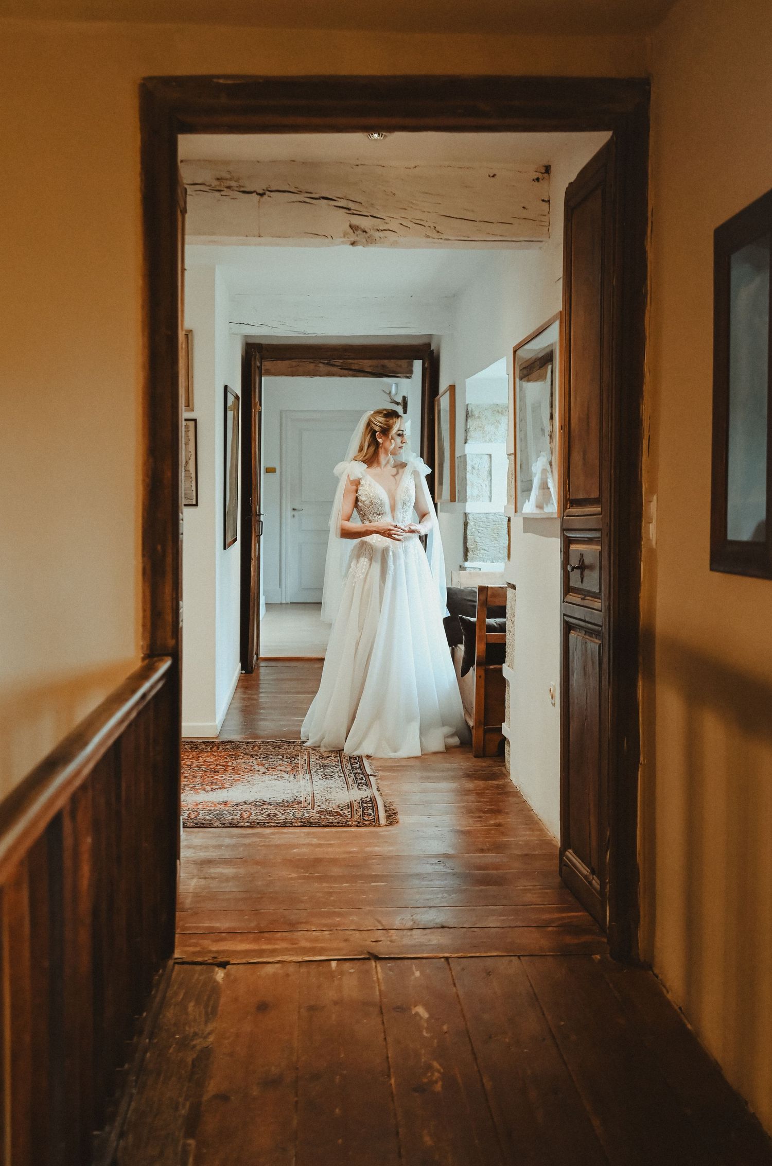Doorway view of a sunlit bridal scene in a vintage interior with wooden floors.