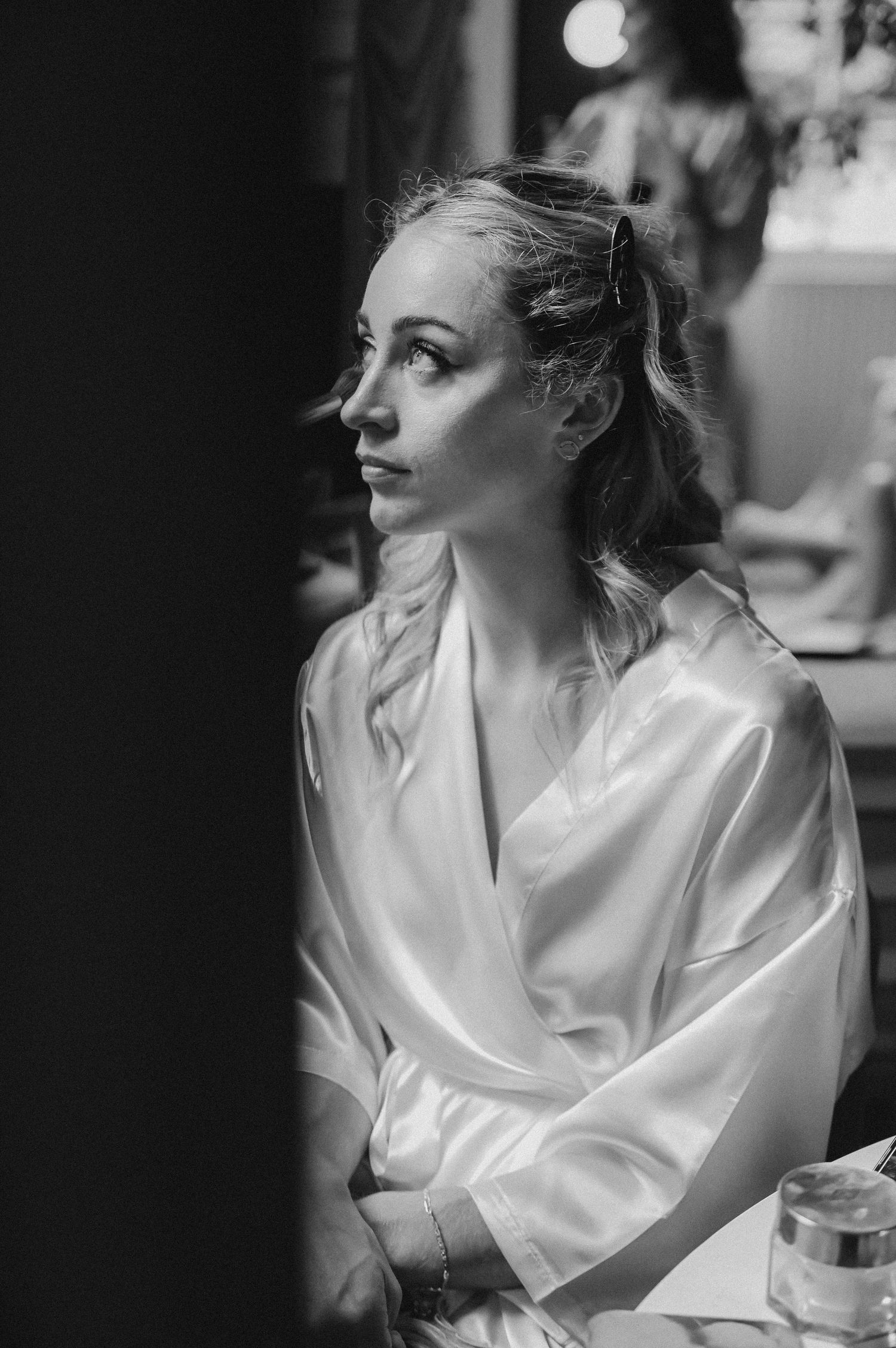 Black and white profile portrait of someone in a silk robe during wedding preparations.