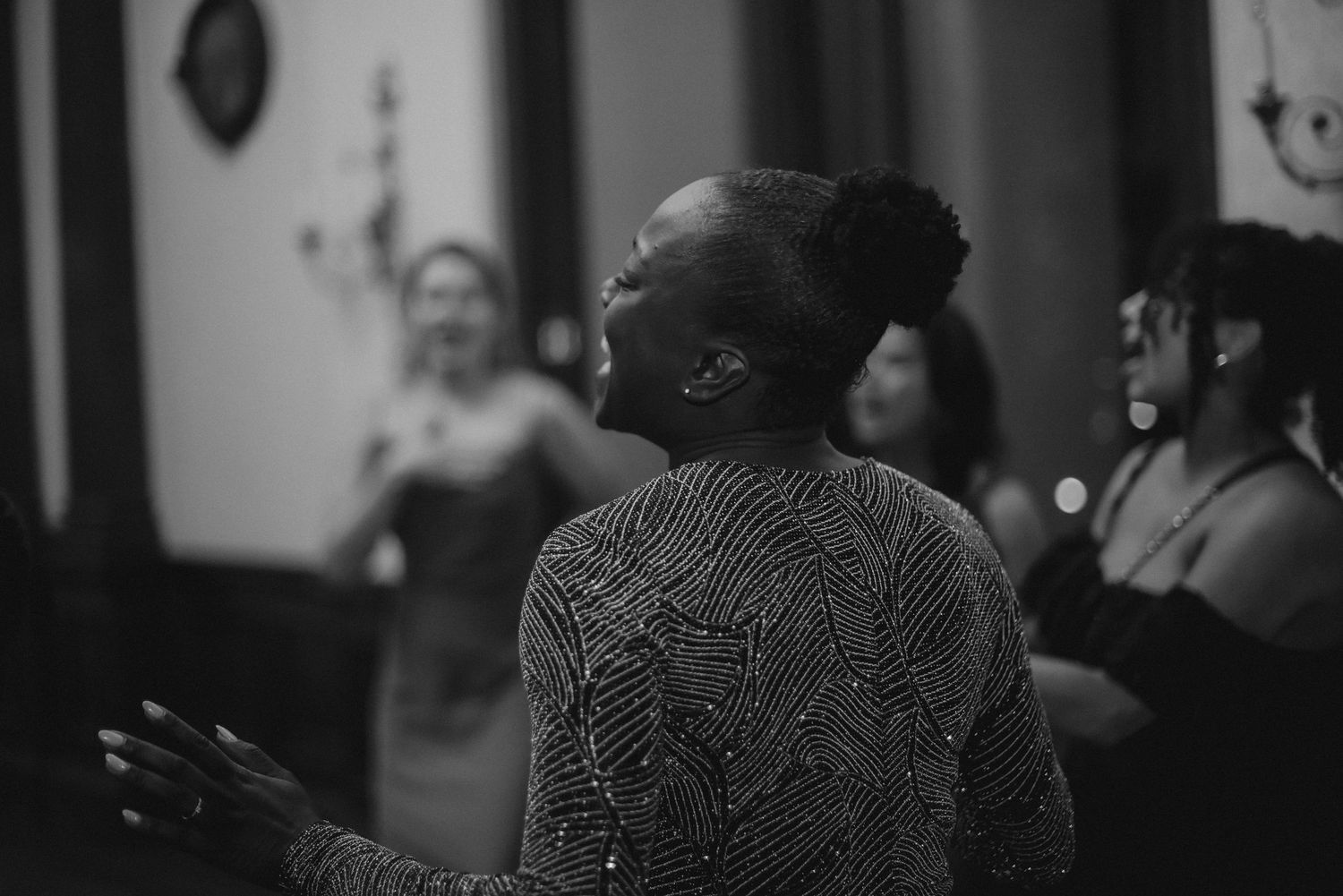 A person in lace attire dances with joy at an indoor celebration.