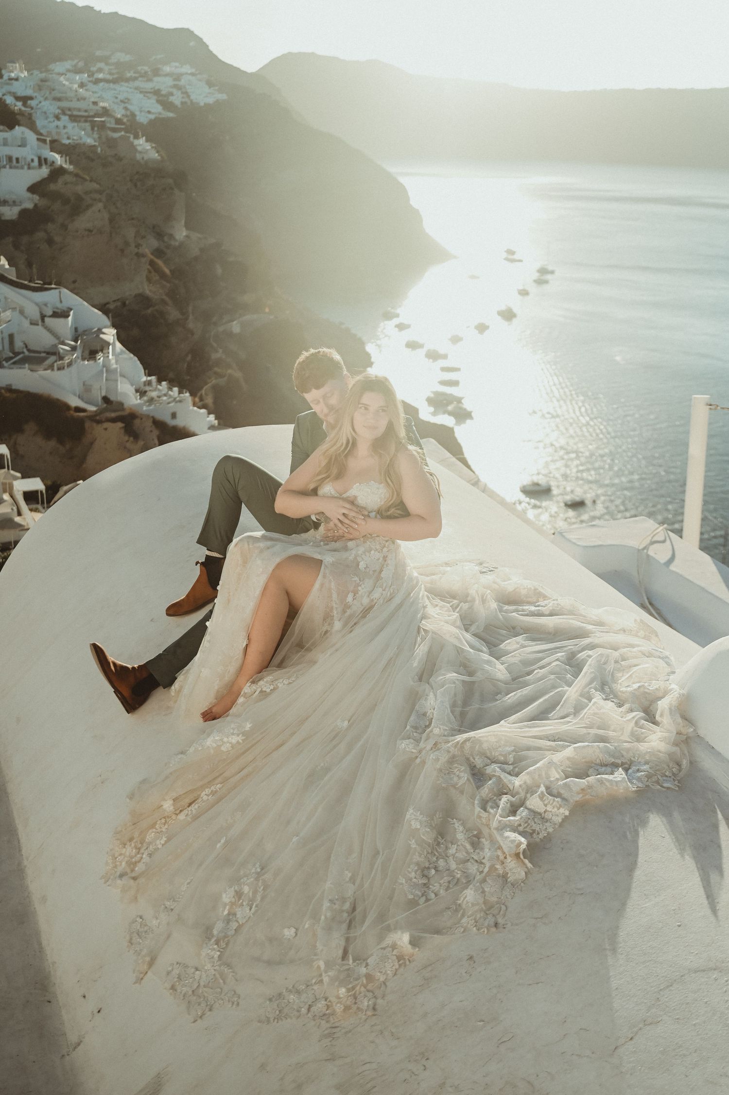Romantic sunset wedding photo on Santorini white walls overlooking Mediterranean sea.