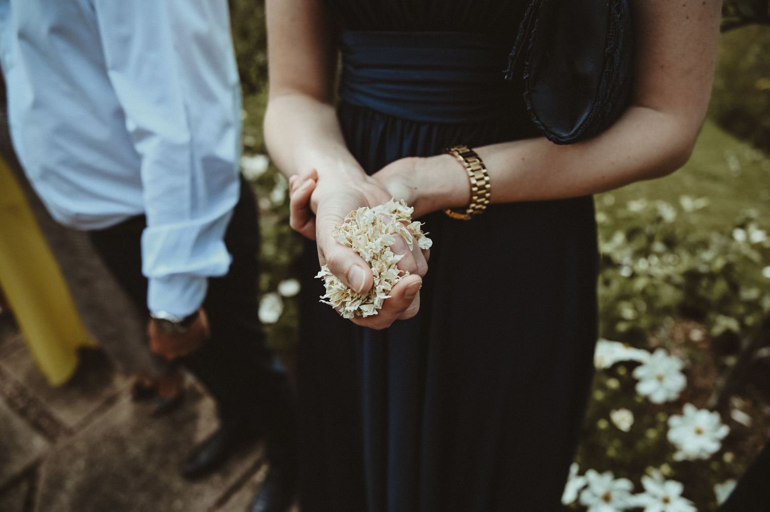 Hands holding delicate white flower petals during a wedding ceremony.
