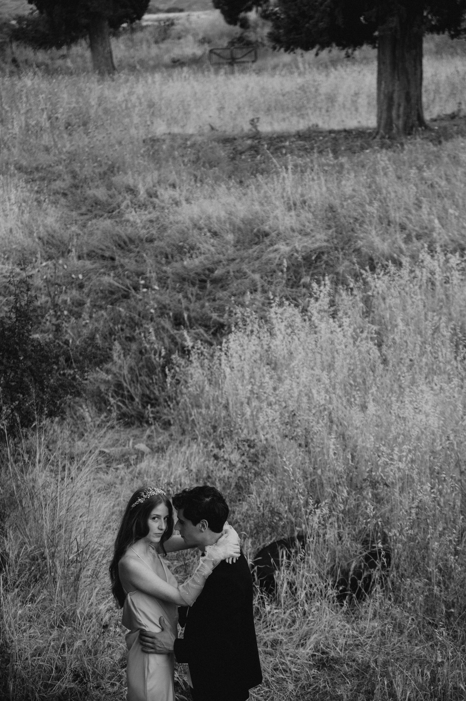 A romantic moment captured in black and white in a field with tall grass.