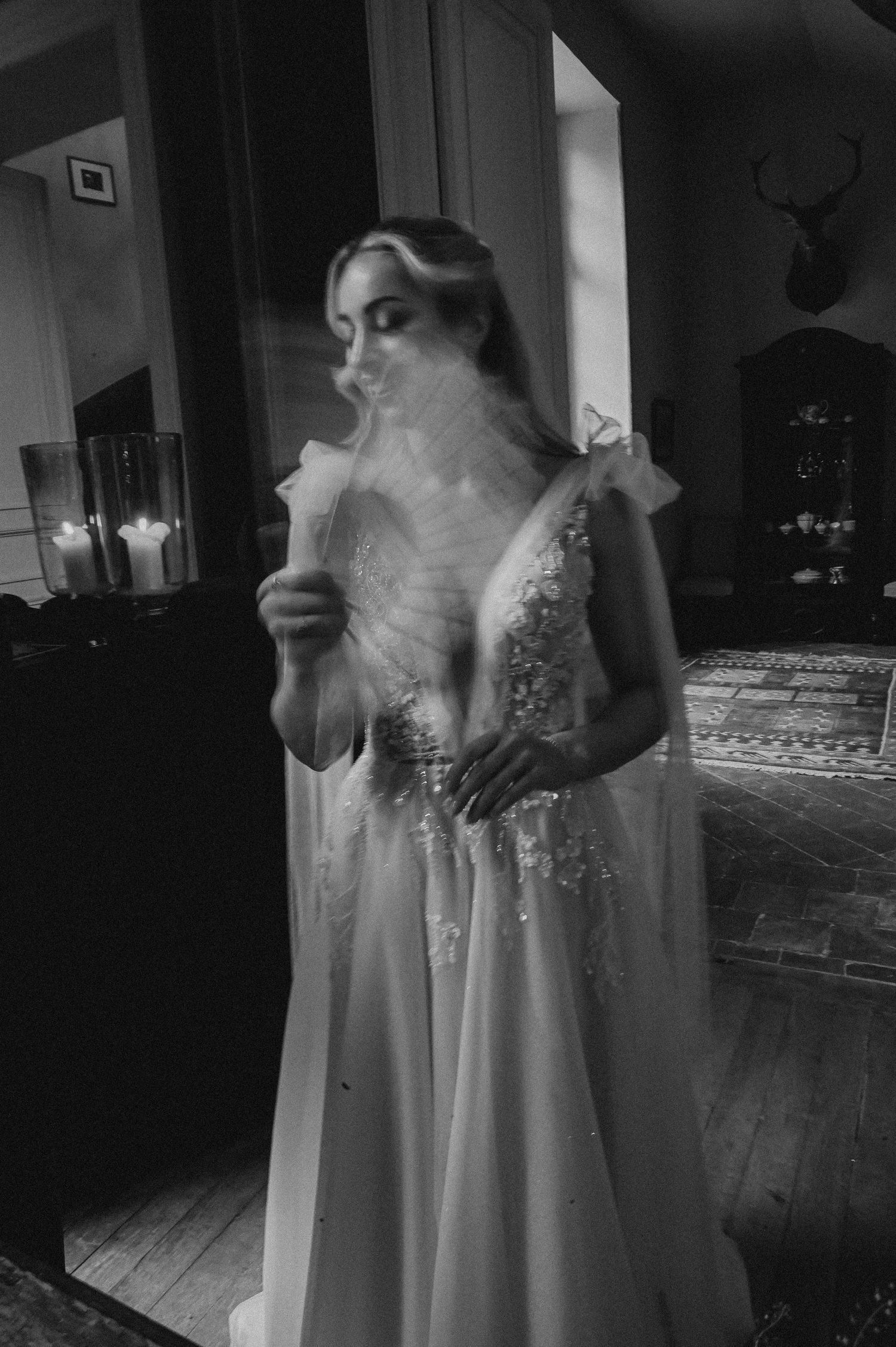 Atmospheric black and white portrait in an elegant room with candlelight and vintage details.