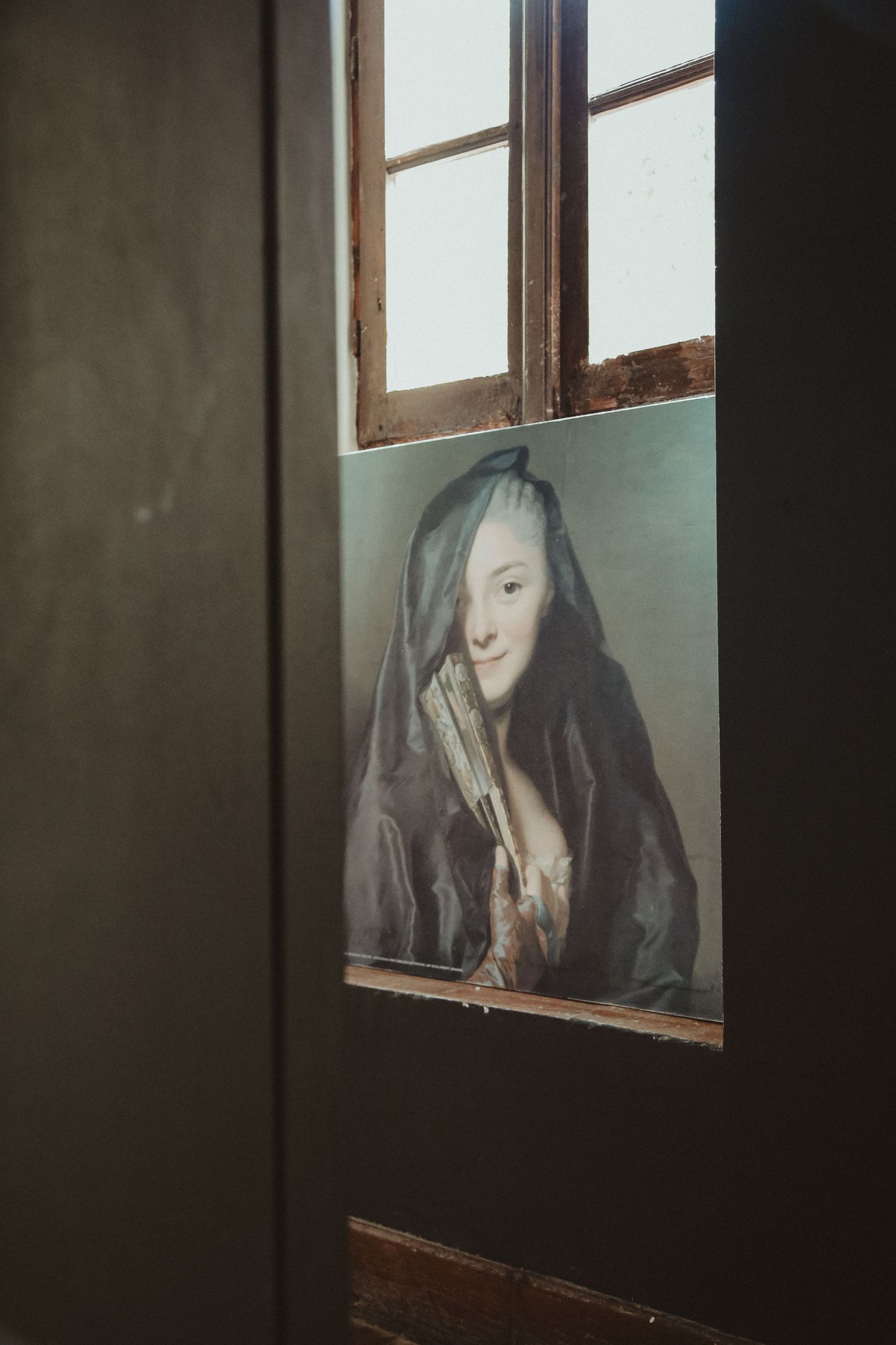 Artistic portrait photograph visible through a window pane in moody lighting.