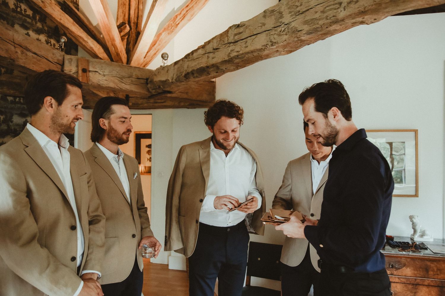 Five people gather in conversation within a rustic room featuring exposed beams and stone walls.