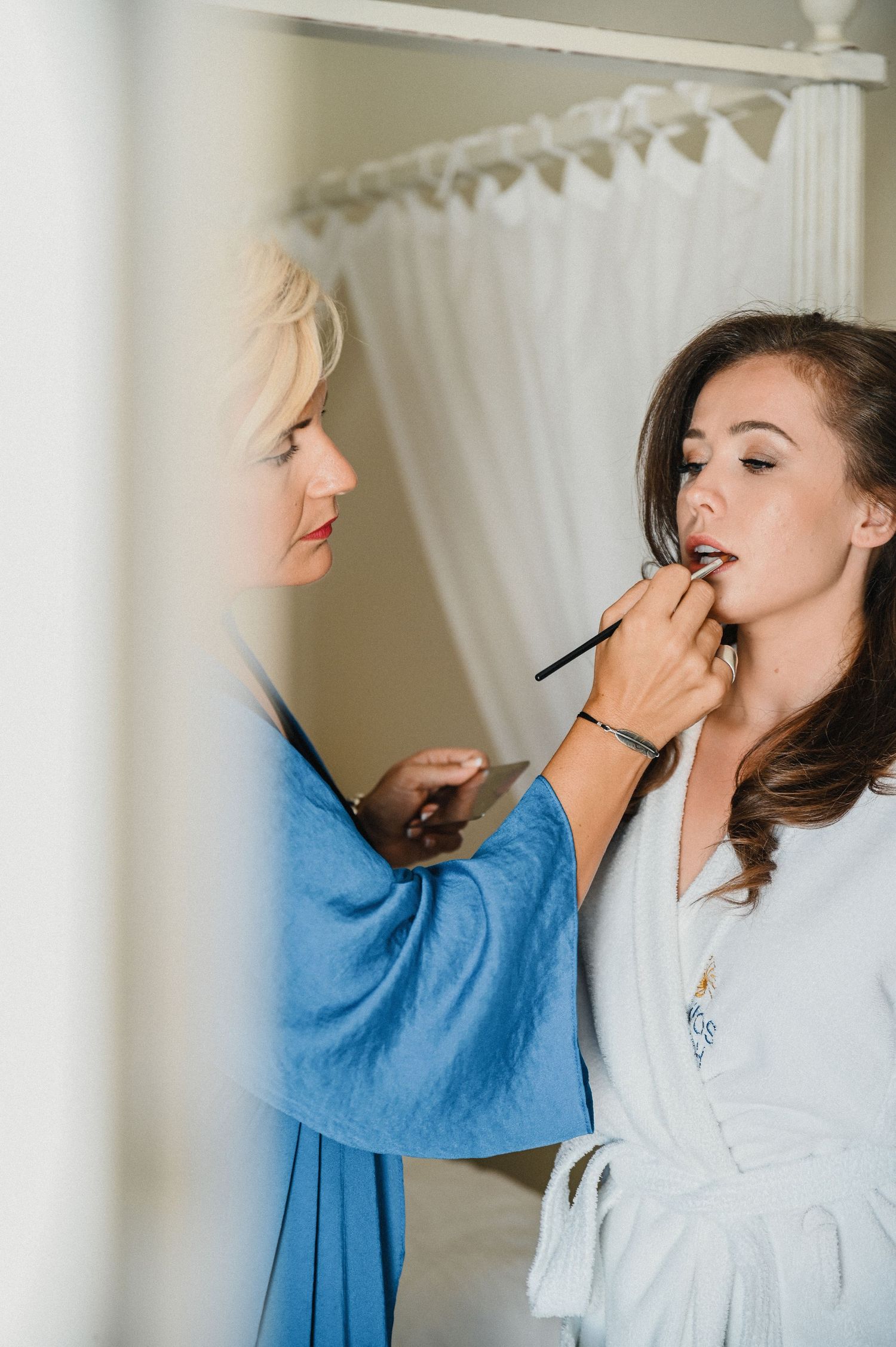 Behind the scenes preparation showing makeup application in a bridal suite.