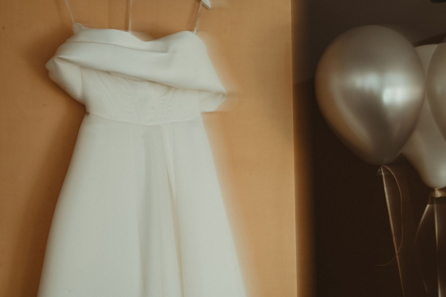 White wedding dress hanging with balloons in soft focus.