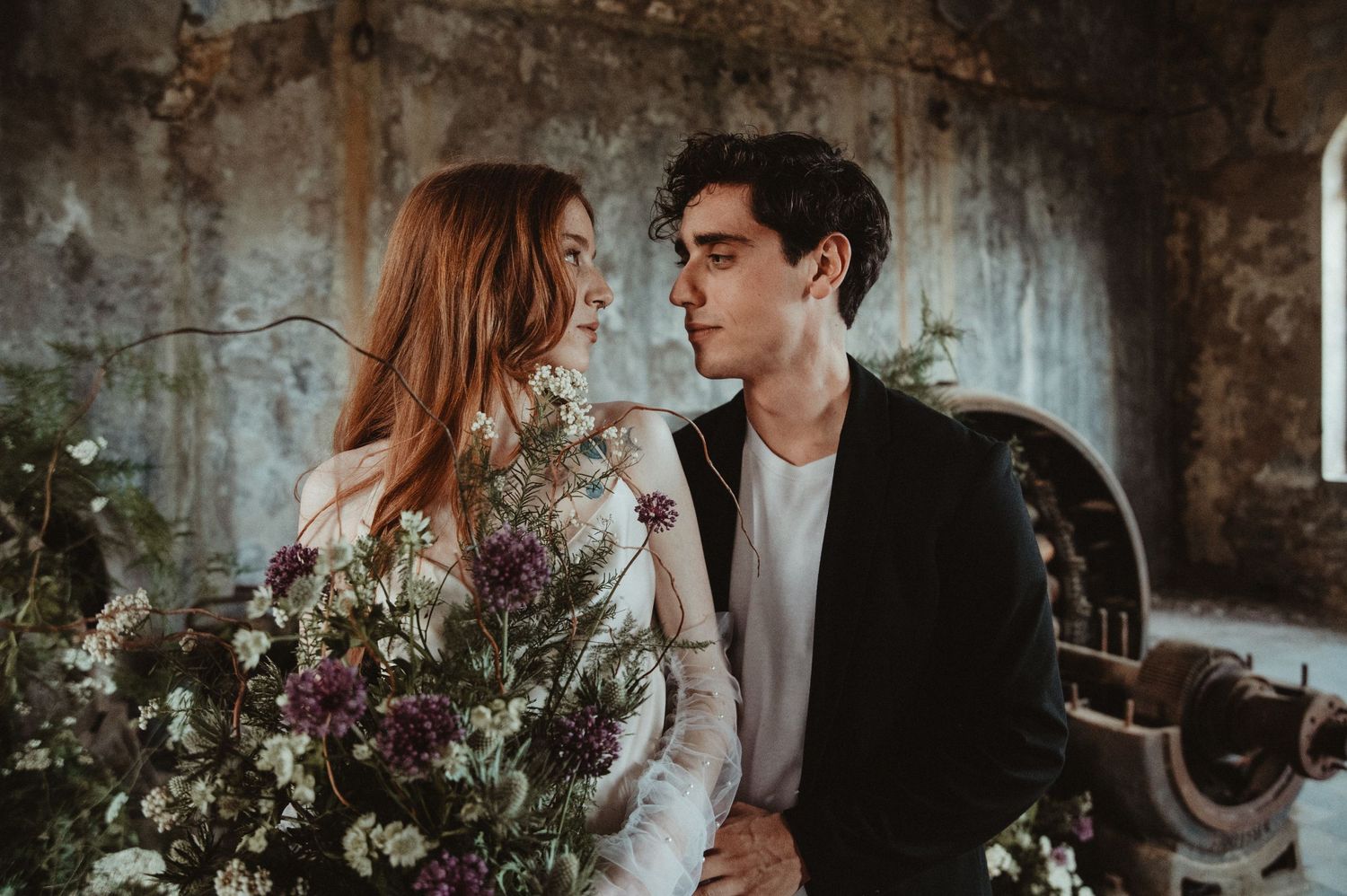 Moody wedding portrait in vintage stone interior with wild flower arrangements.