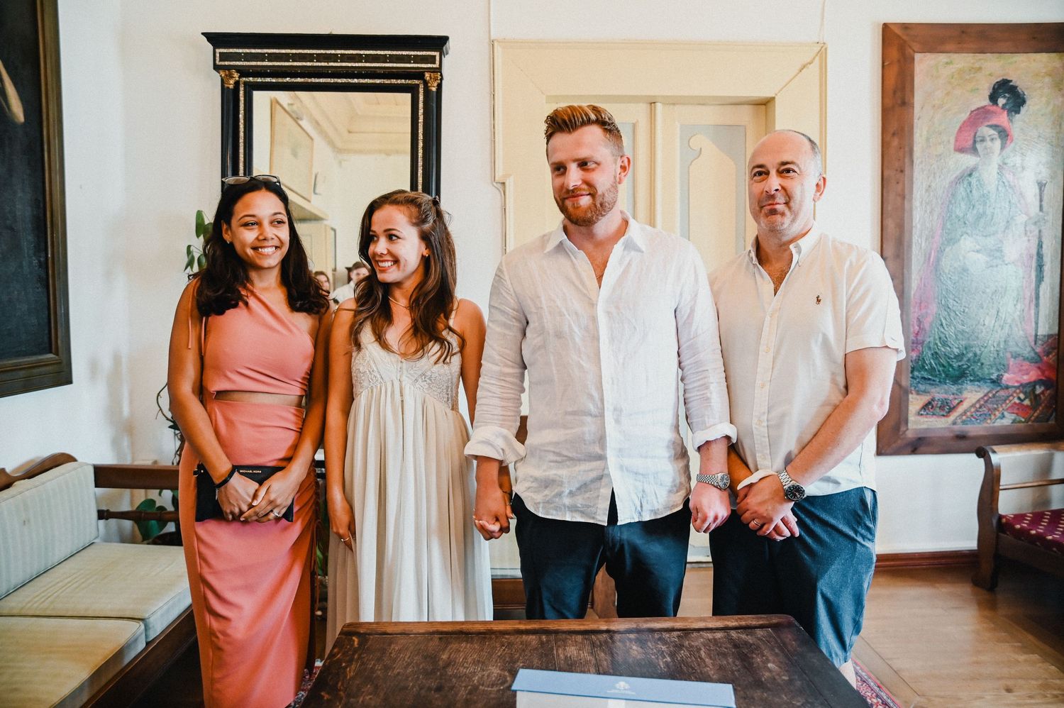 A group stands together at a formal gathering in a room with framed artwork.