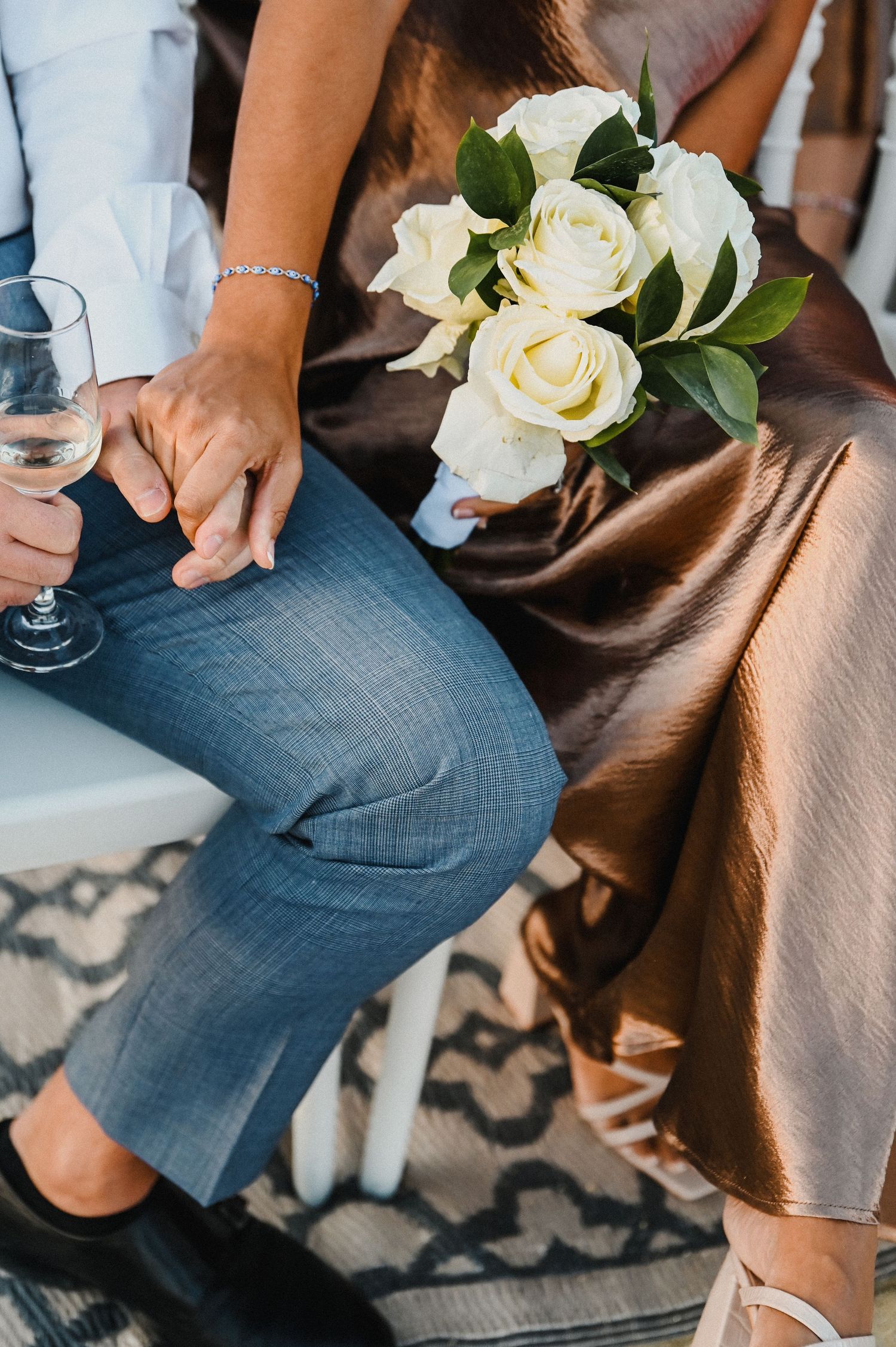 White roses and wine glasses on a table with denim and silk details at an elegant wedding.