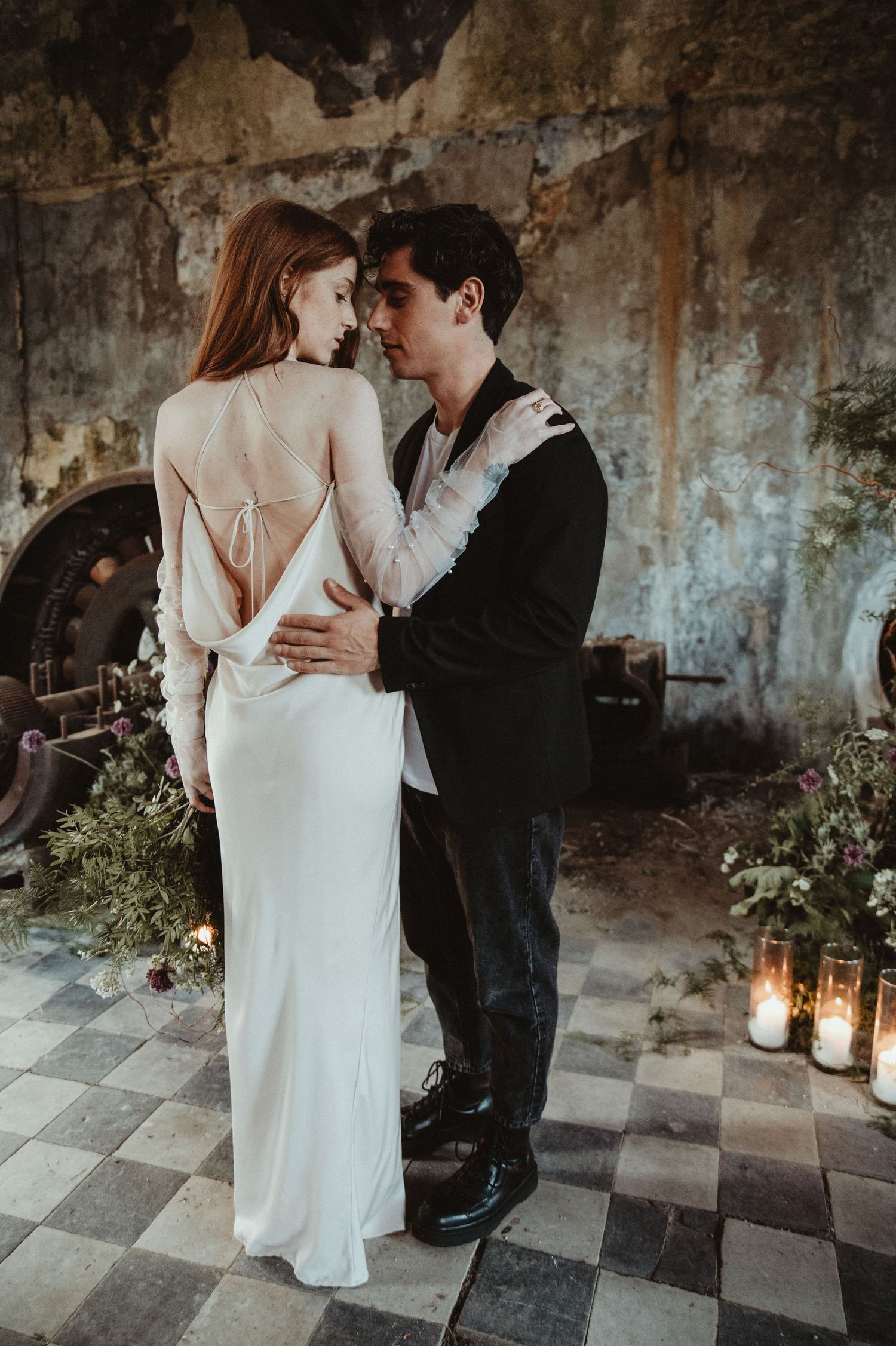 Romantic wedding scene in an old building with checkered floor and lanterns.