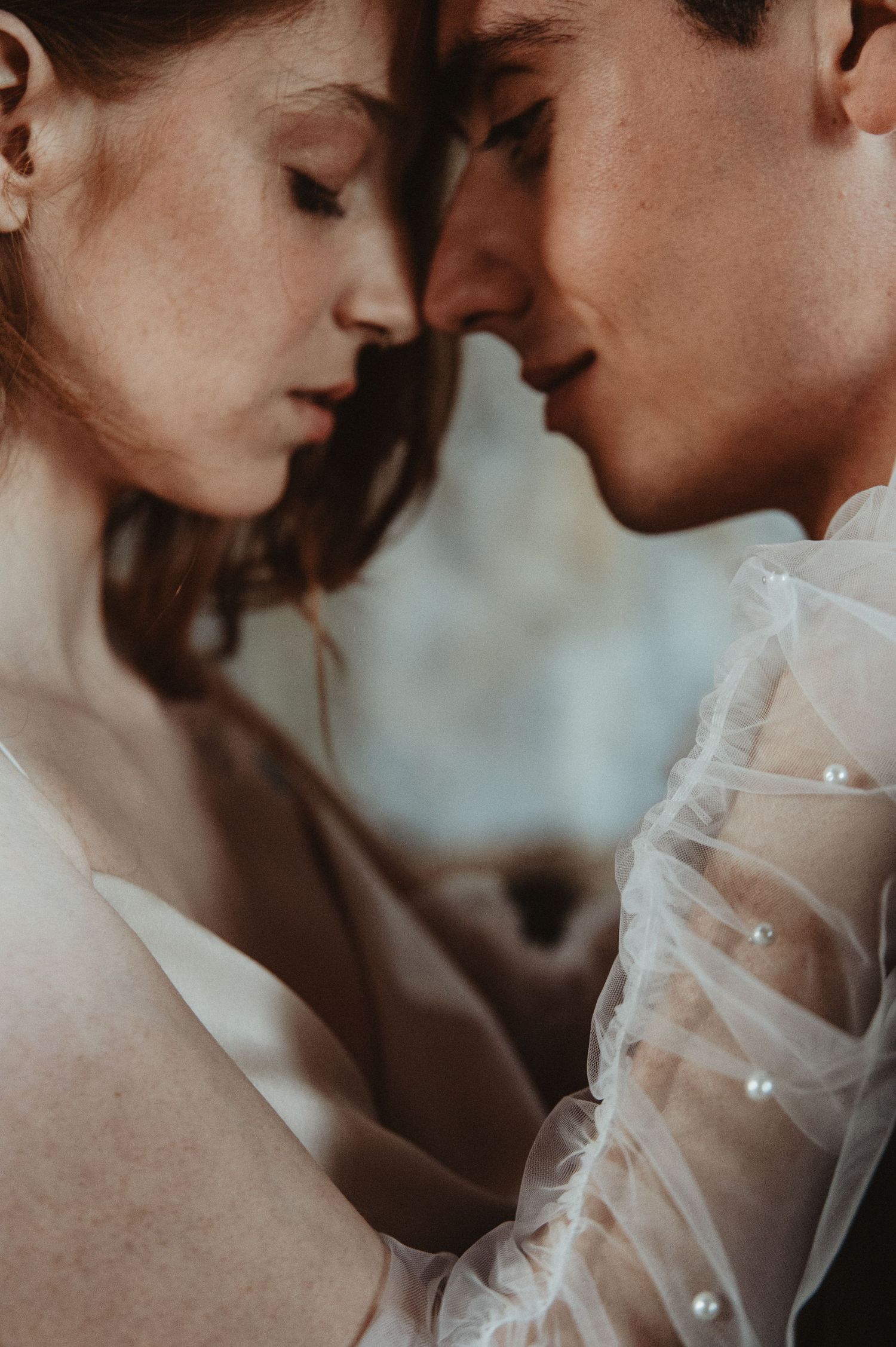 An intimate bridal portrait featuring delicate sheer sleeves and soft romantic lighting.